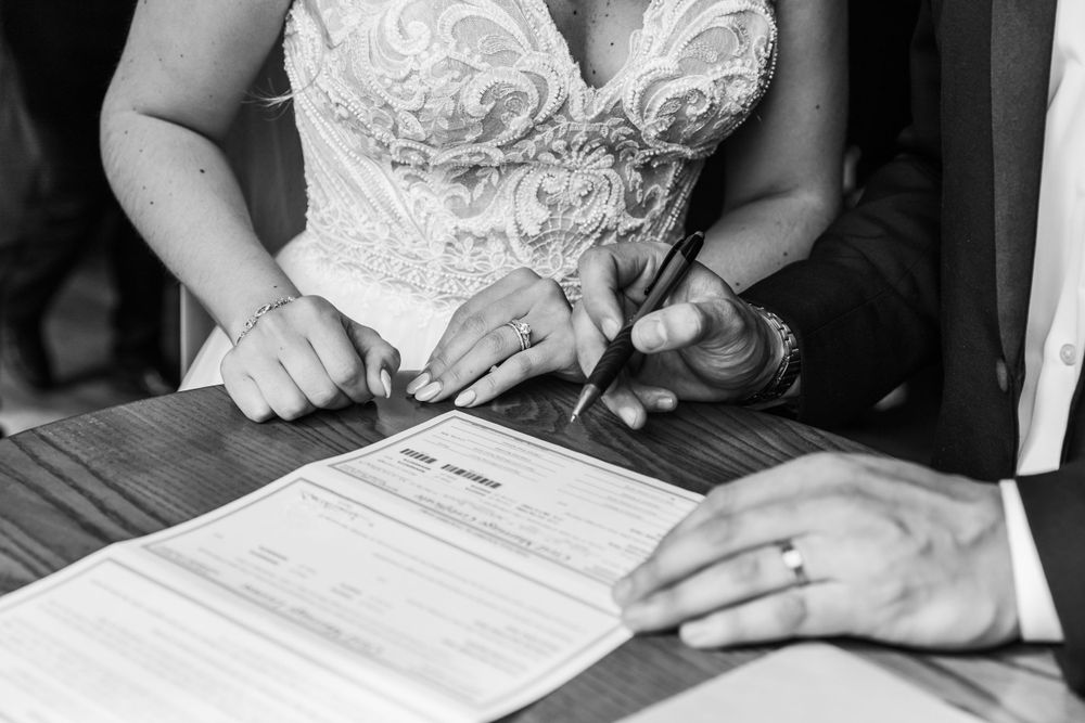 Close-up of hands signing wedding documents during ceremony.