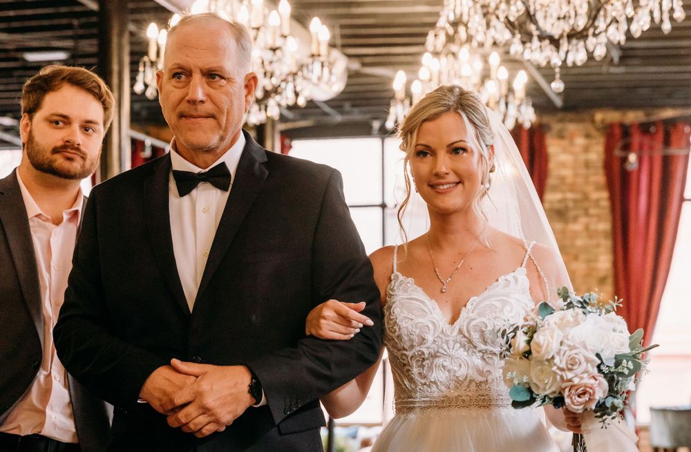 An elegant wedding scene in a venue with exposed brick walls and crystal chandeliers.