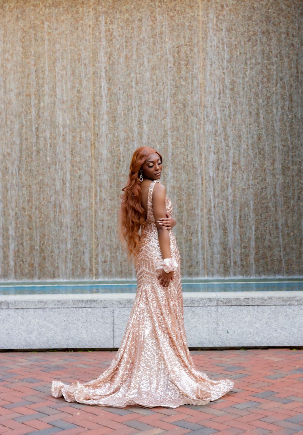 Person in sparkling rose gold dress twirls on brick patio.