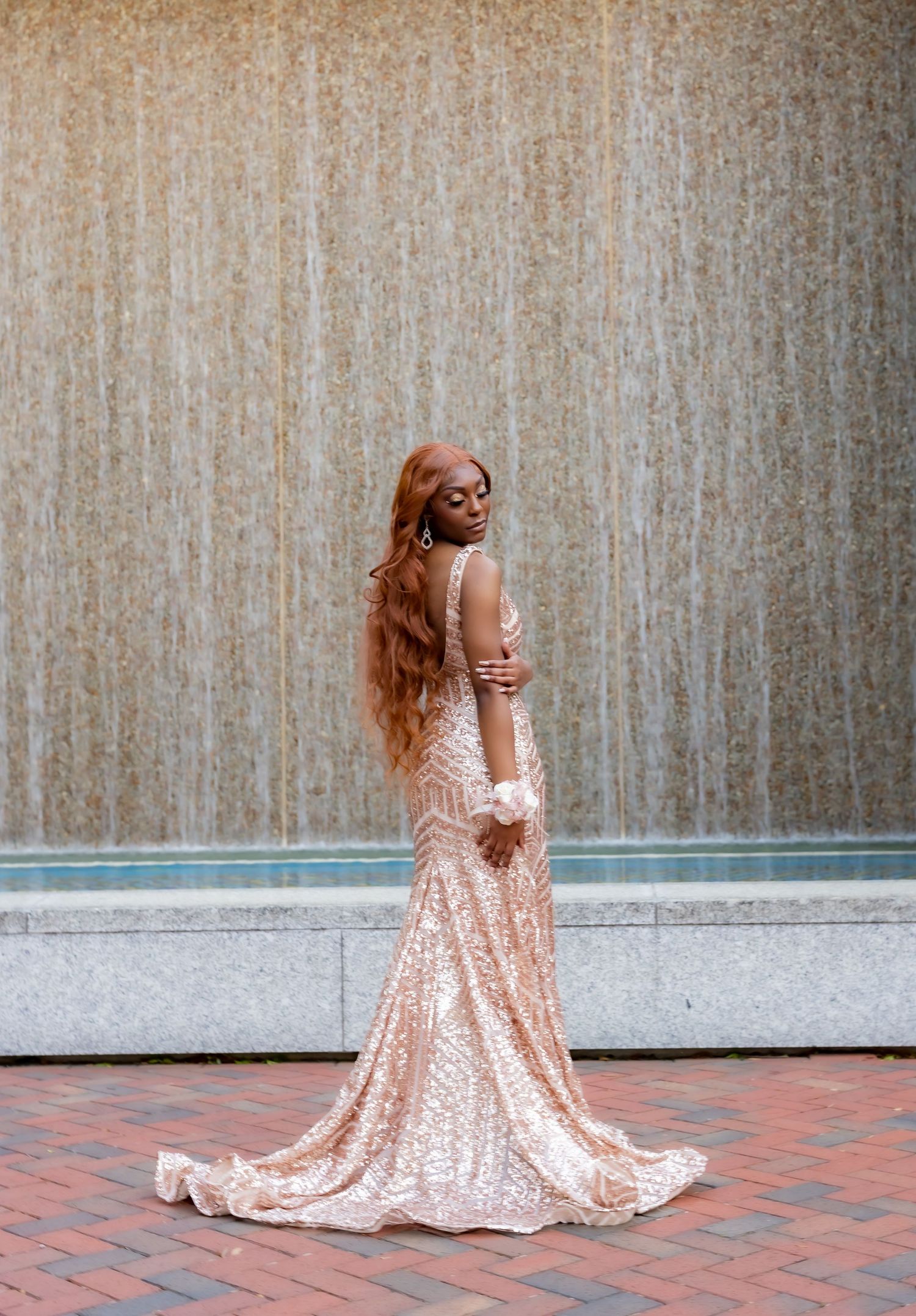 Person in sparkling rose gold dress twirls on brick patio.