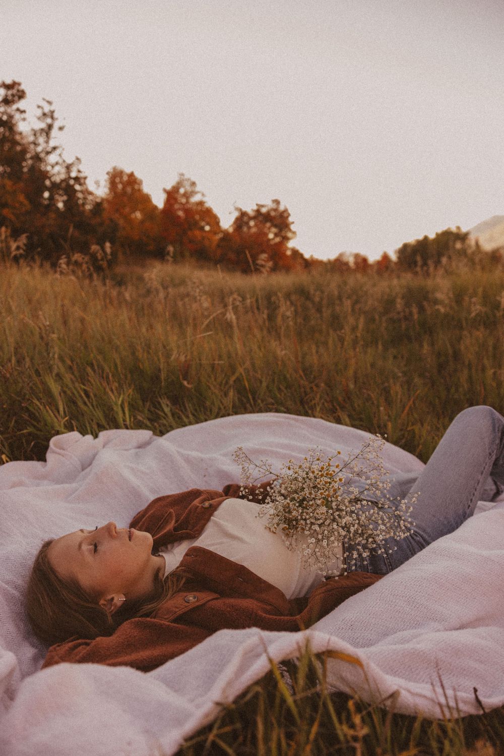 Relaxed autumn portrait on white blanket with dried flowers.