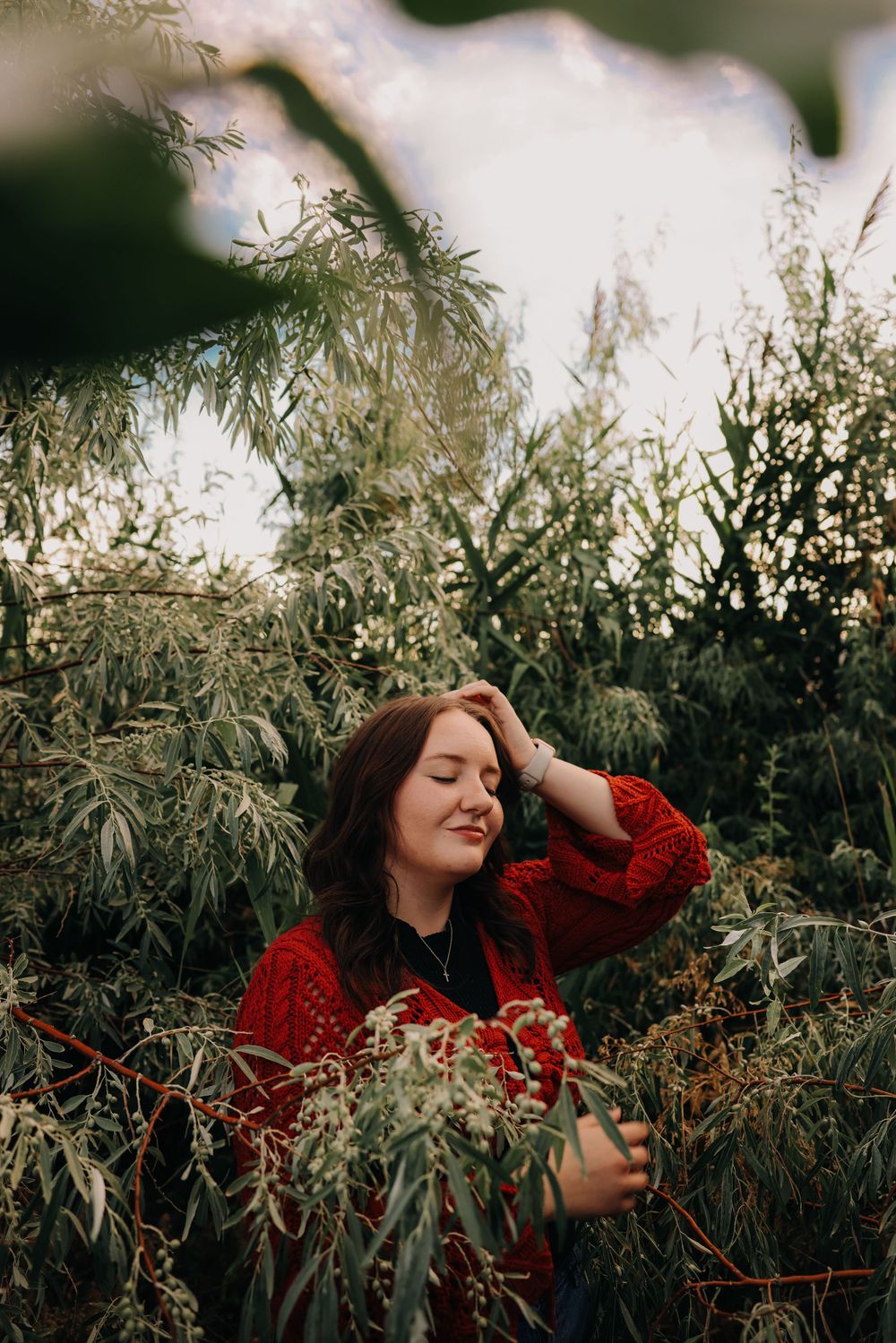 Someone in bright red sweater surrounded by wispy natural foliage.