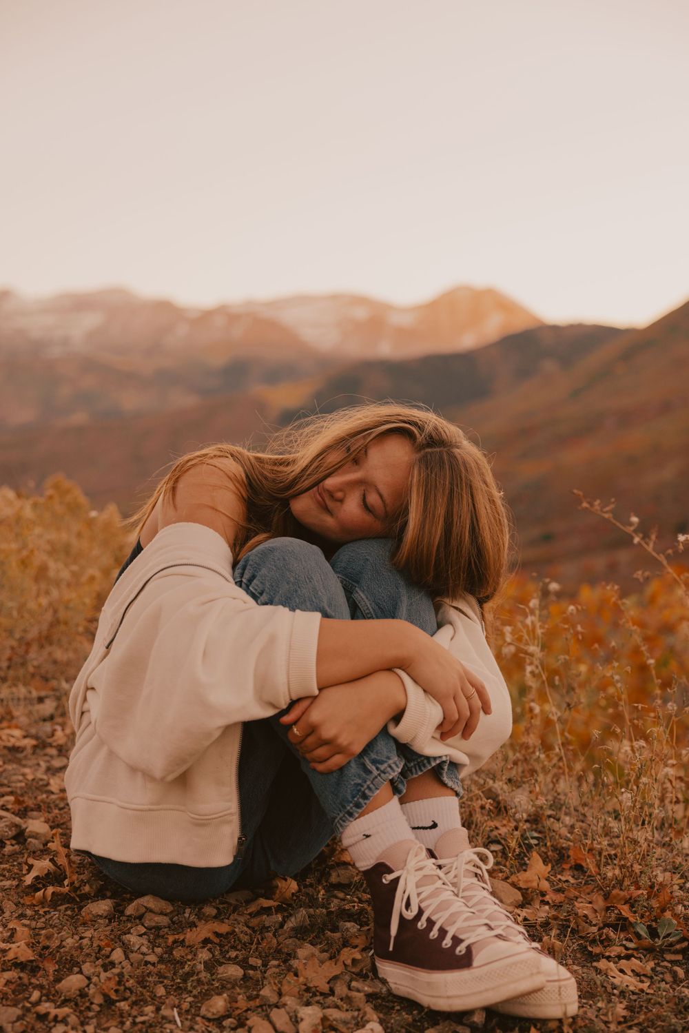 A cozy autumn scene with someone resting in a casual pose against golden mountains at sunset.