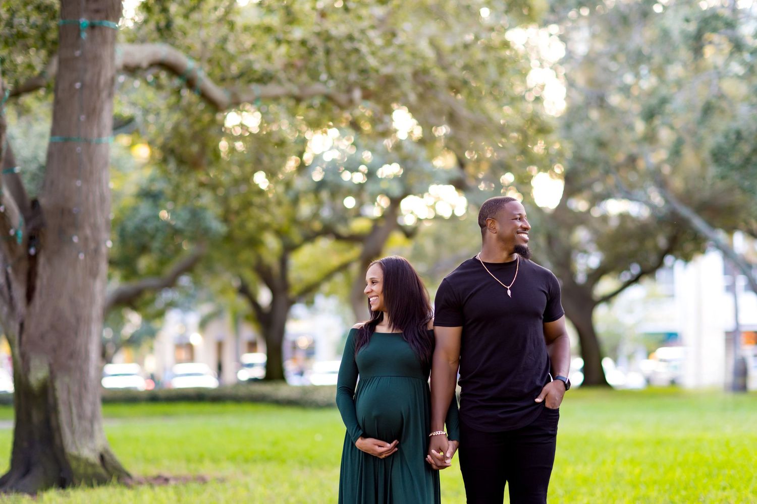 Expecting couple walks together in park setting during maternity photoshoot.