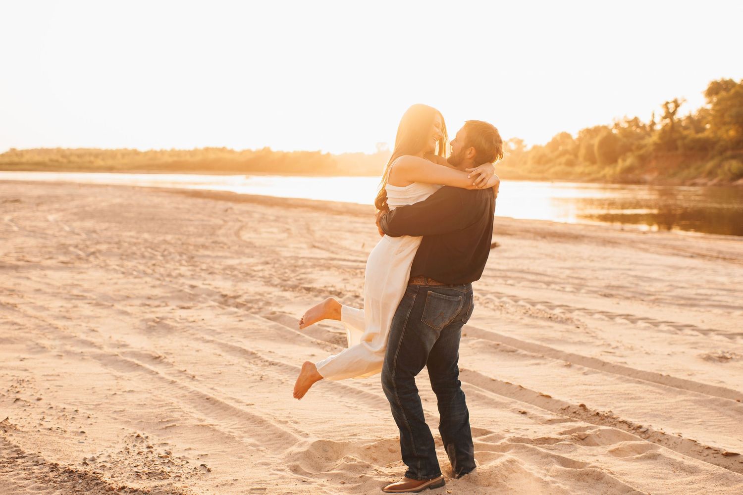 A warm, romantic photograph of a couple sharing a tender moment at sunset