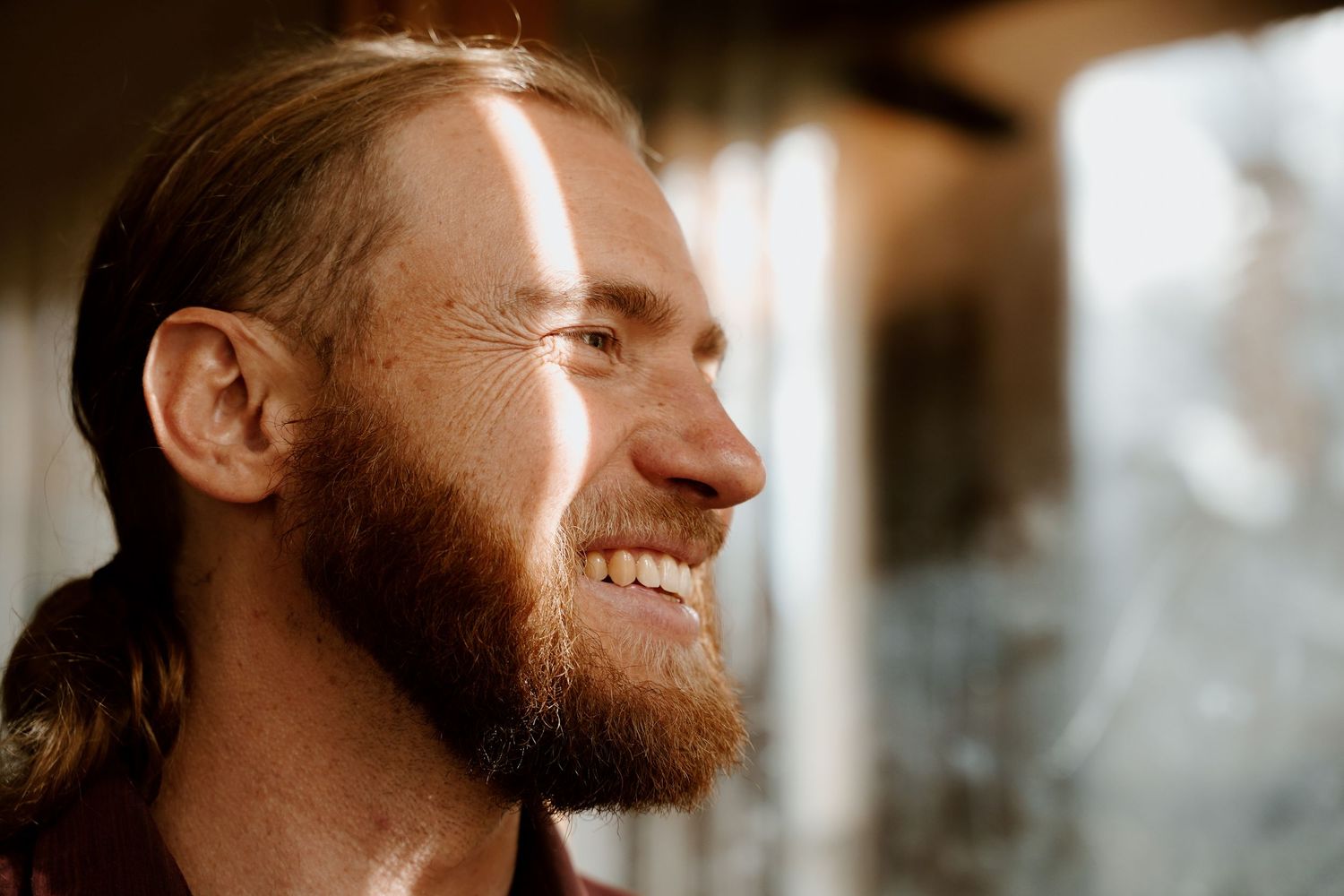Profile view of bearded person smiling in warm sunlight.