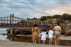 gorgeous family photoshoot, sunset, cloudy and moody vibe. family holding hands at the beach