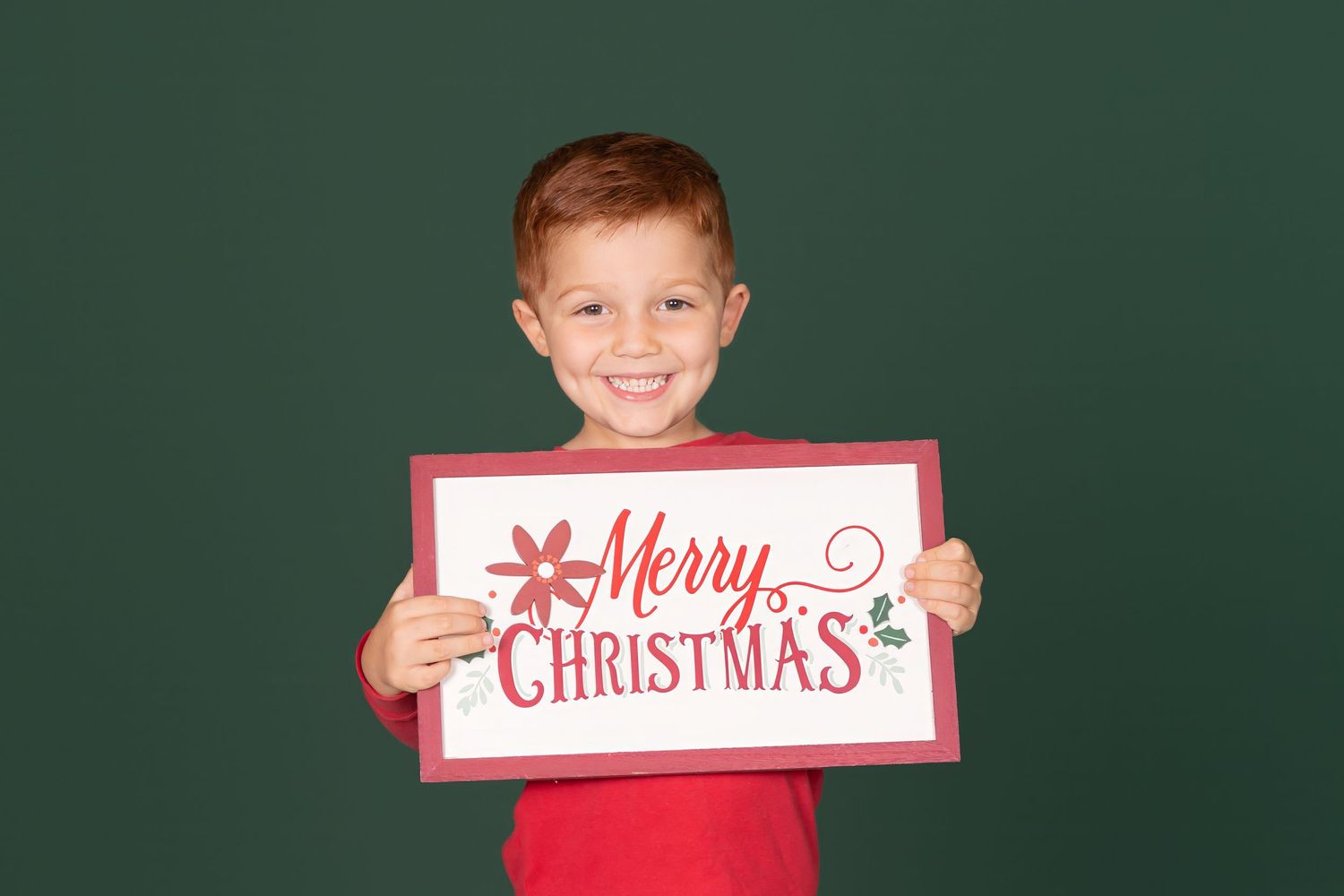 child holding merry christmas sign on solid green backdrop in studio clayton new jersey Gloucester county