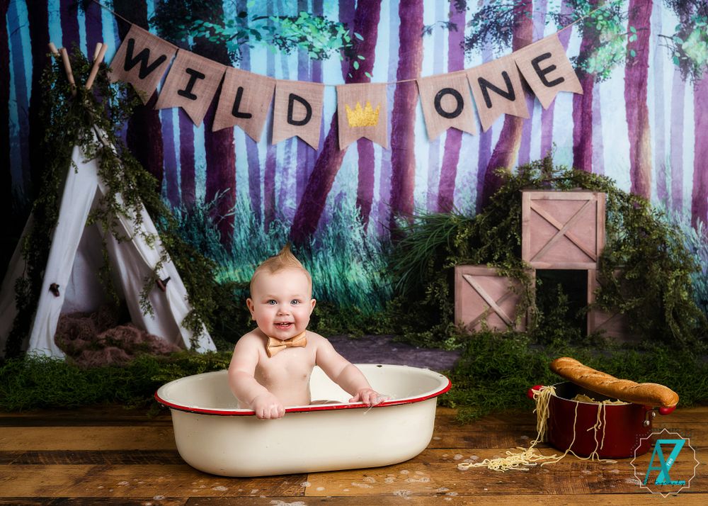 First birthday photoshoot featuring vintage white tub and woodland theme with decorative banner.