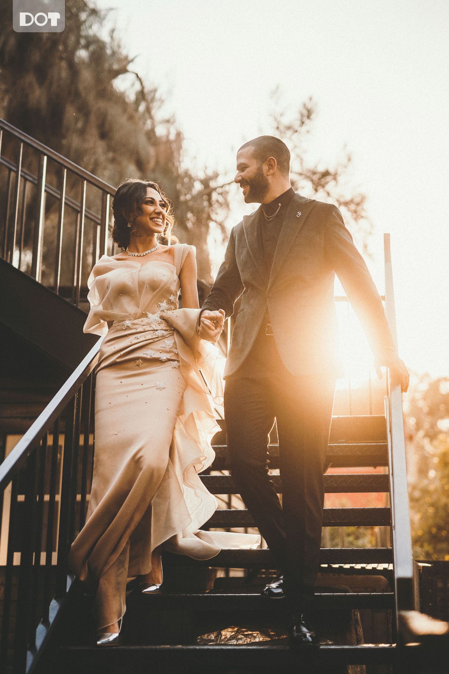 A couple shares a romantic moment on outdoor stairs during golden hour.