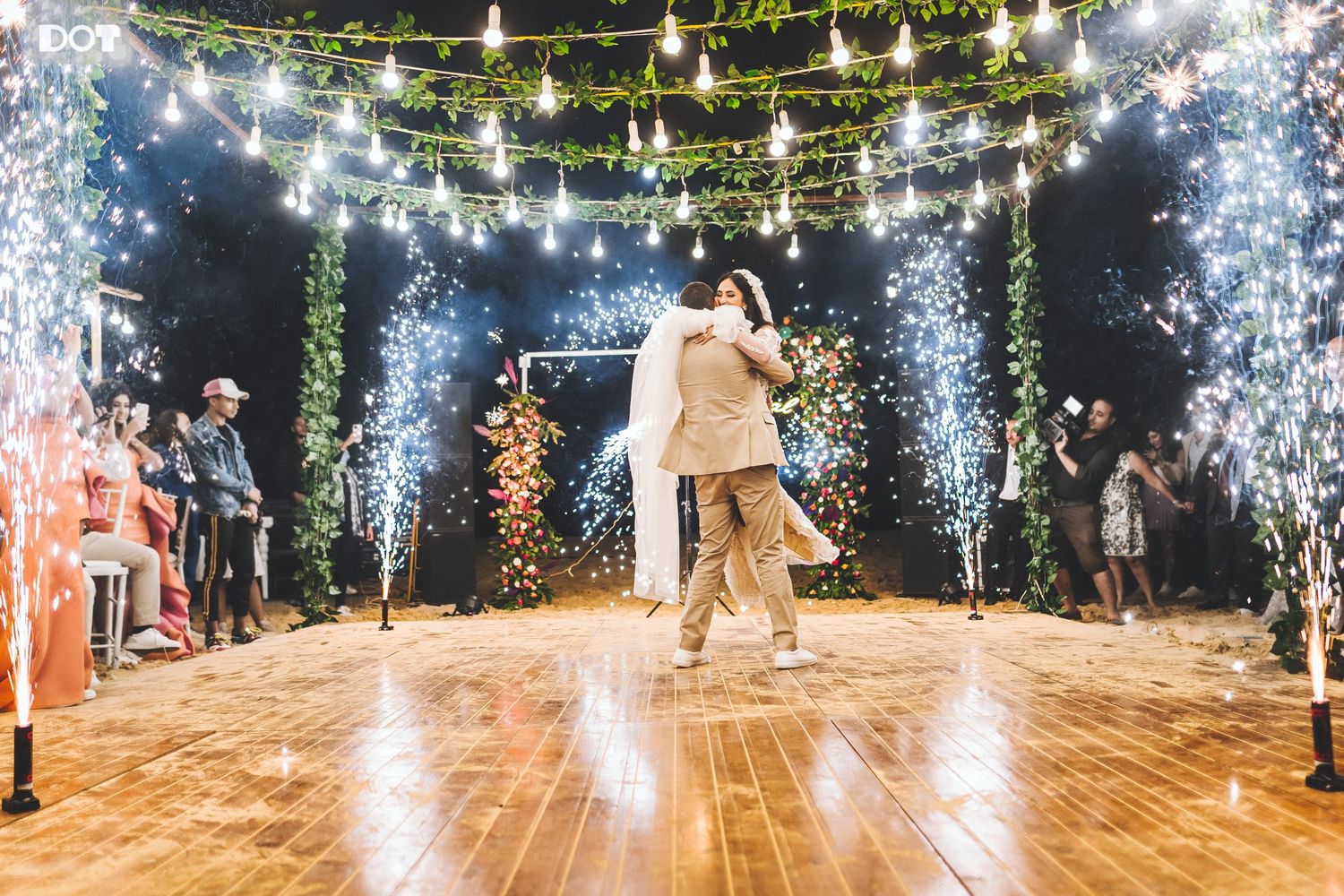Wedding dance floor with string lights and sparkler effects creating magical celebration atmosphere.