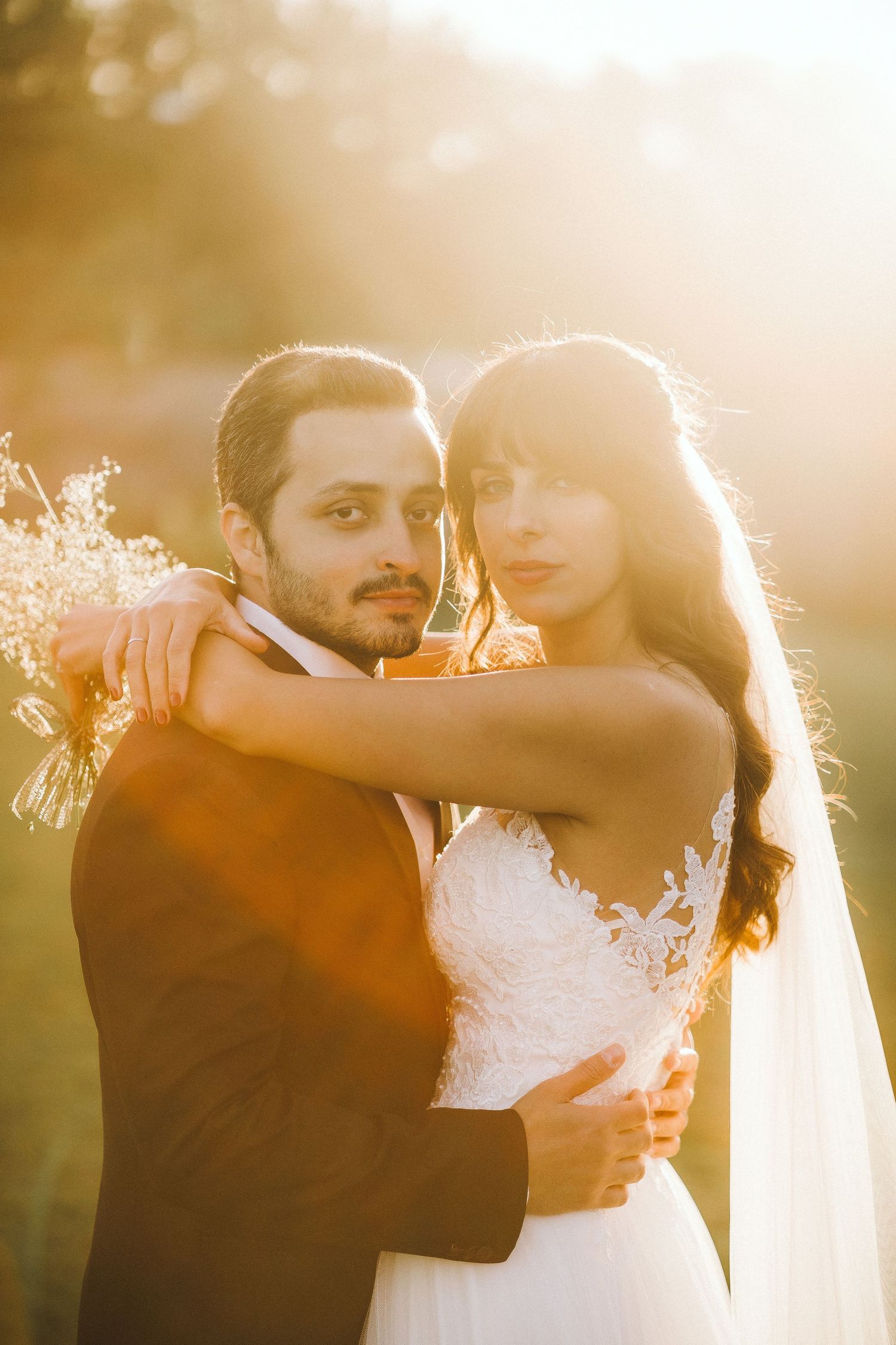 A romantic golden hour wedding photo shoot showing tender embraces in warm sunlight.