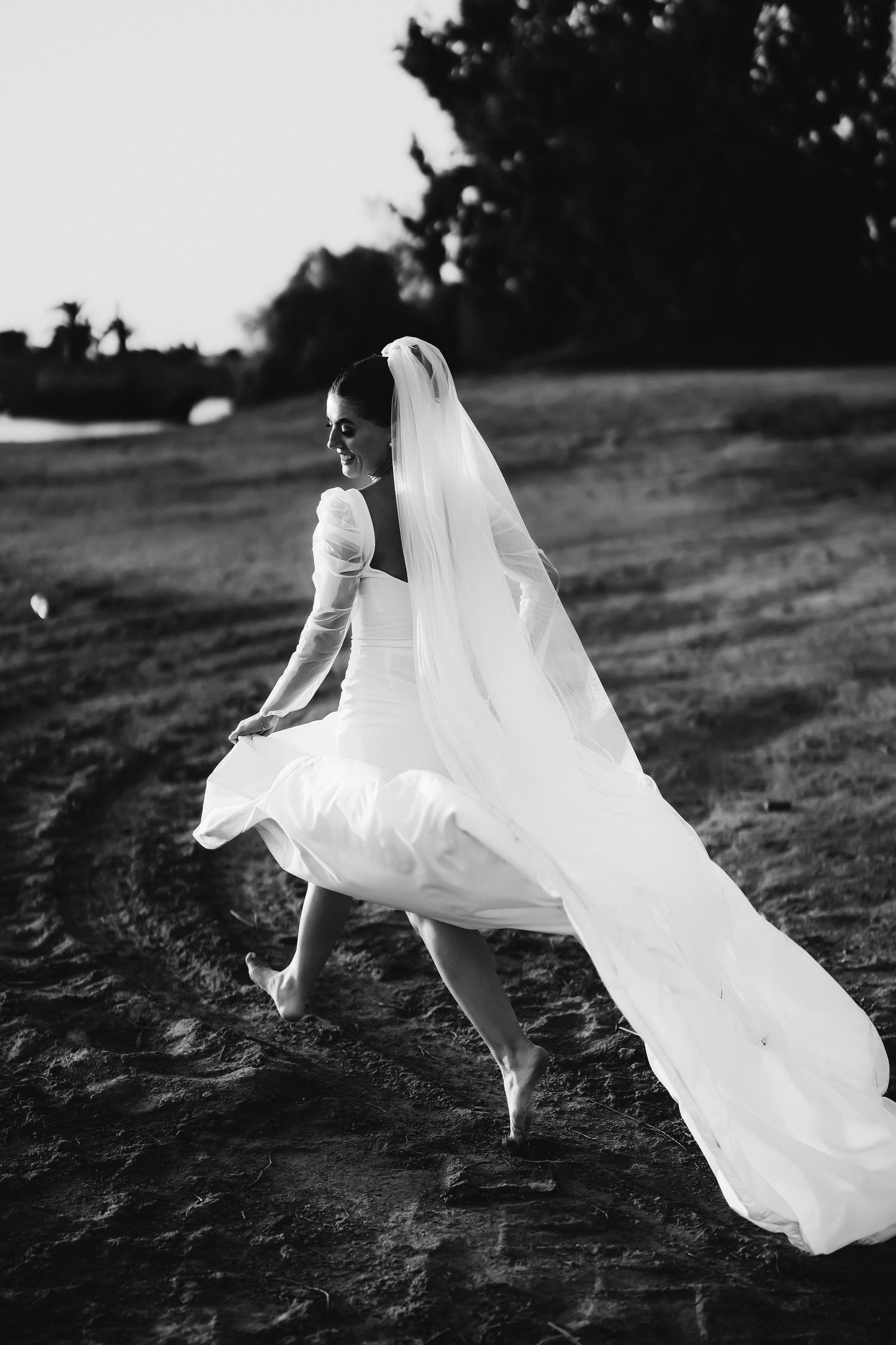 Black and white photo of flowing wedding dress fabric caught in motion against dark background.