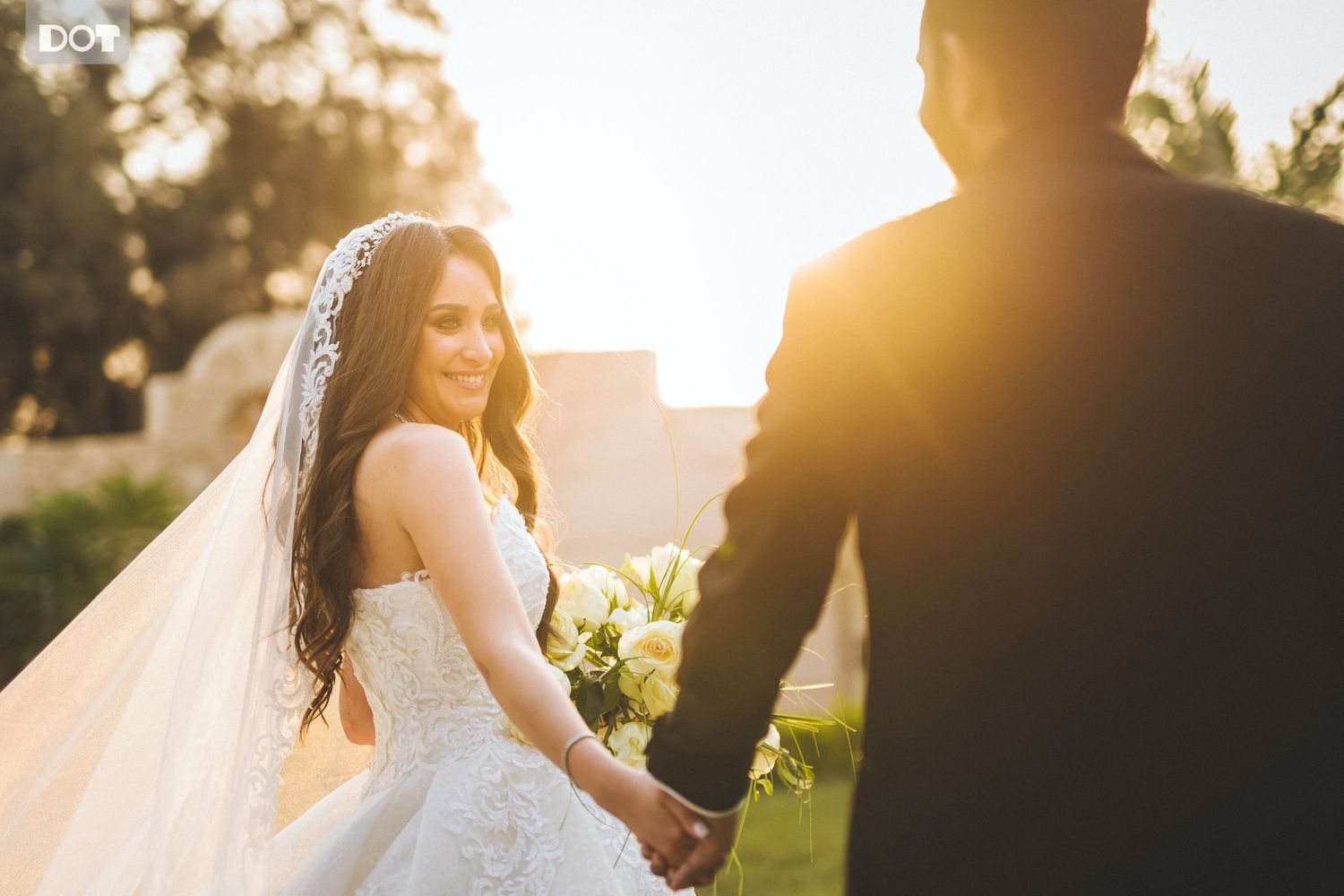 Romantic sunset wedding portrait with golden light streaming through couple's silhouette.