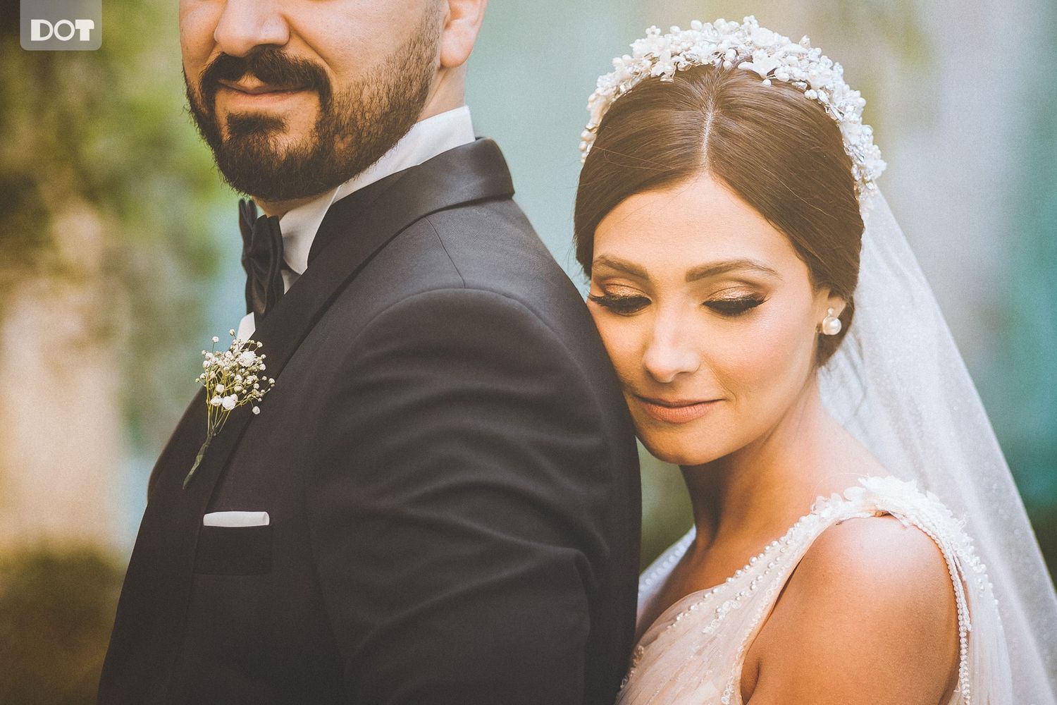 An intimate wedding portrait showing the bride's veil and groom's profile against a soft background.