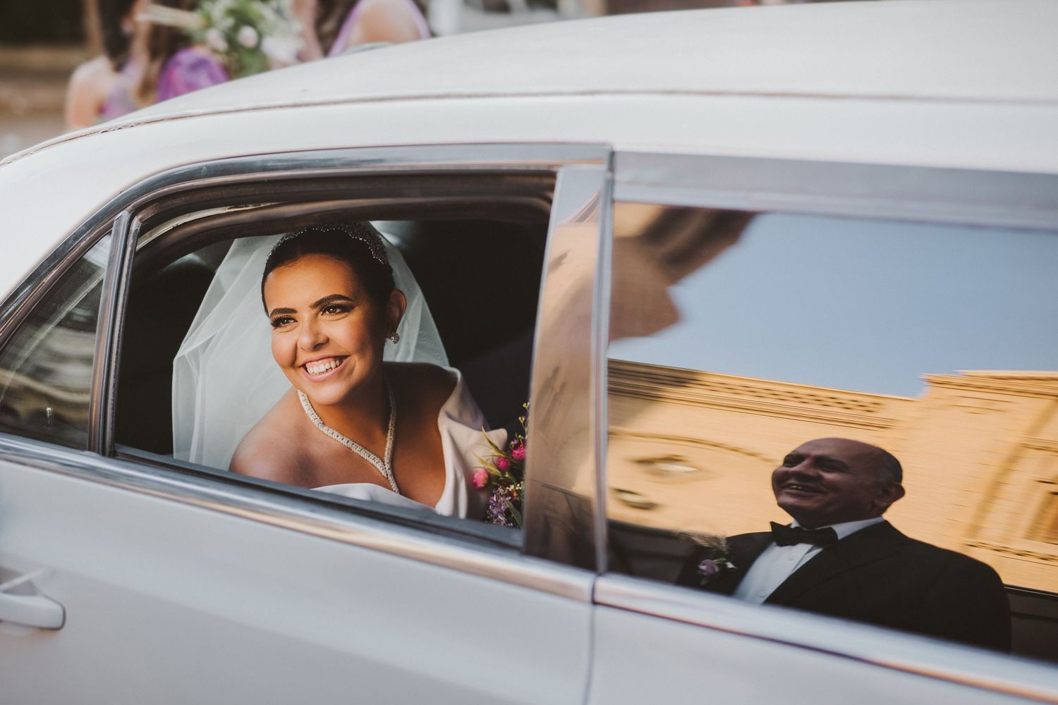A line of cars with wedding decorations parked in a row.
