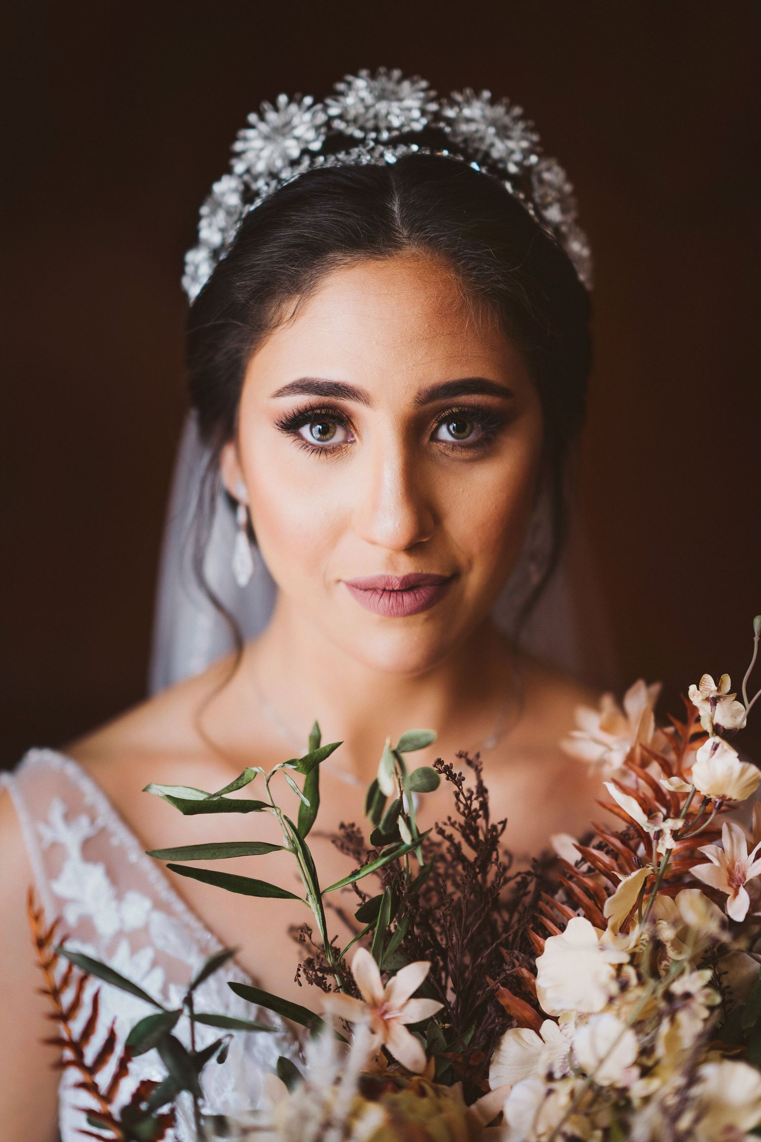 Bride holding an elegant autumn-toned bouquet with white and burgundy flowers.