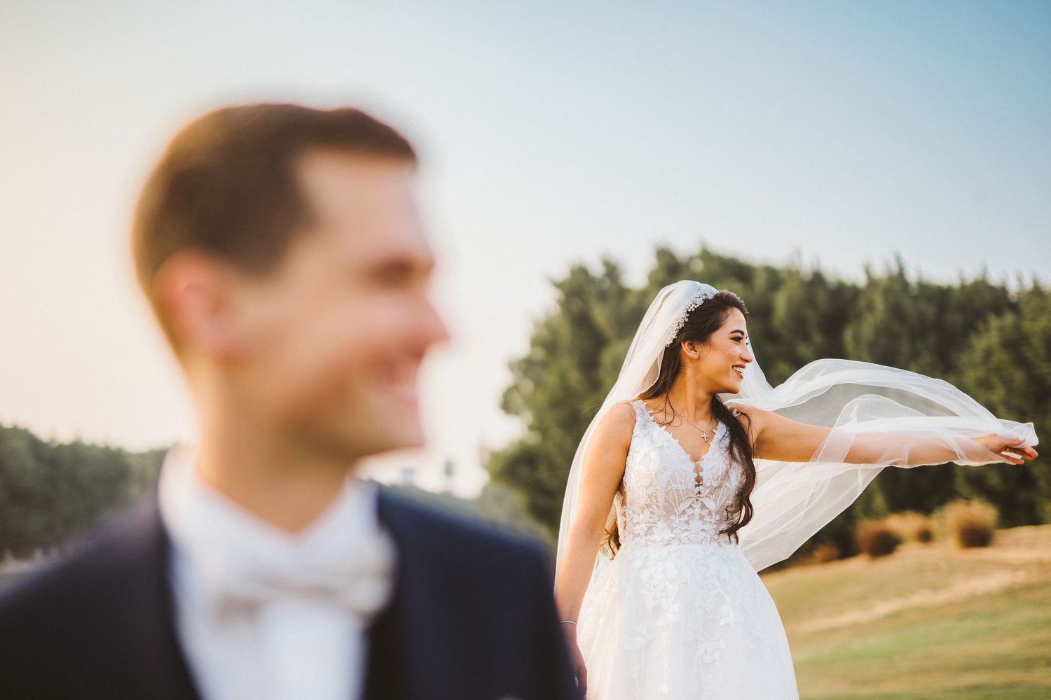 Wedding couple poses in a scenic outdoor field during golden hour.