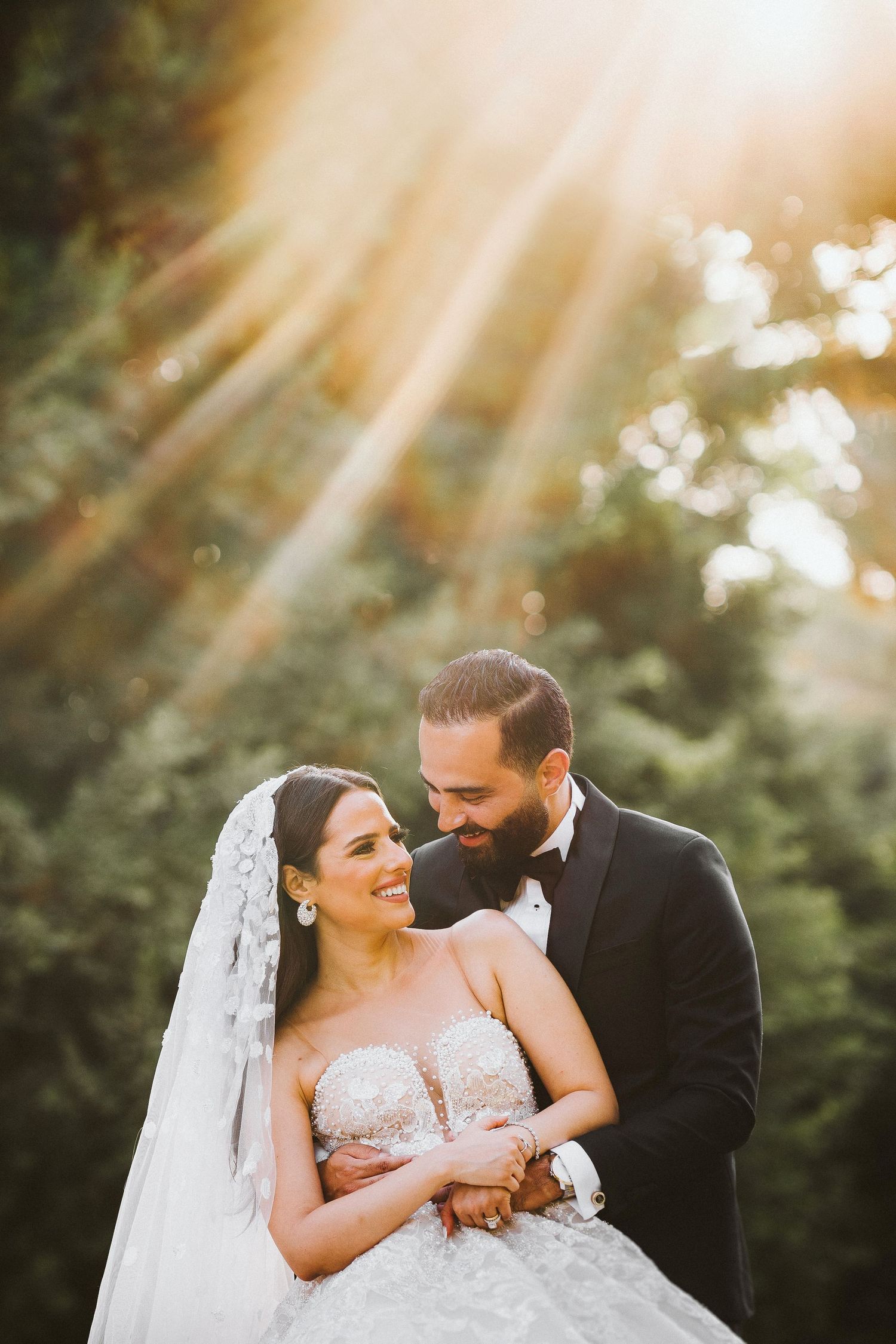 Newlyweds share intimate moment in golden sunlit garden setting.