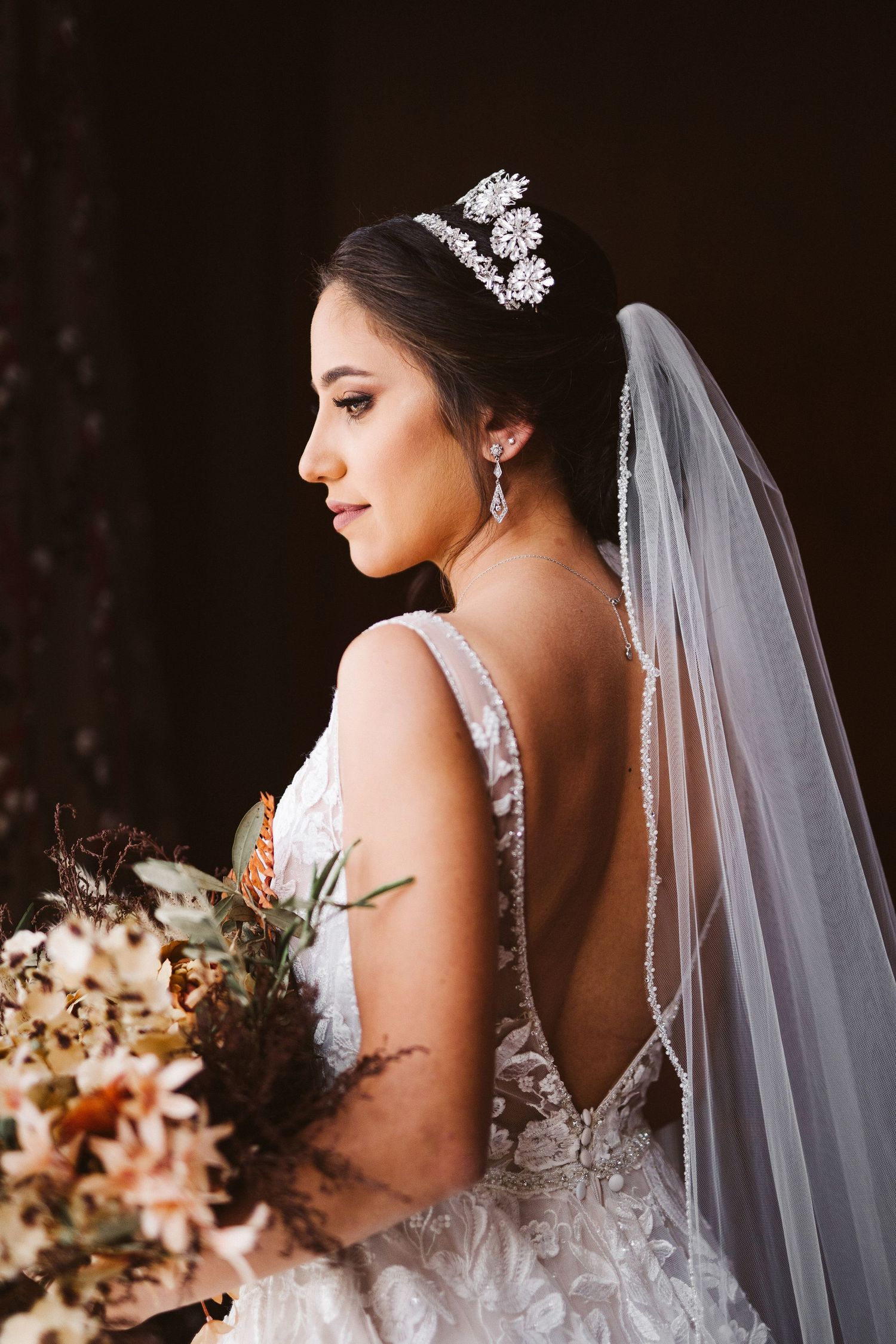 Side profile of bride wearing crystal crown and holding autumn bouquet.