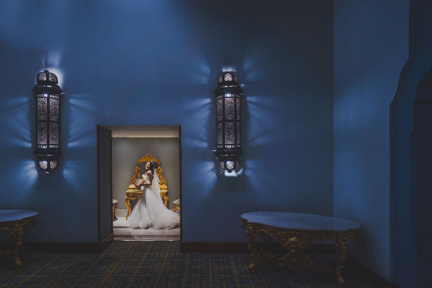 Moody blue-lit hallway with hanging lanterns creating dramatic wedding venue atmosphere.