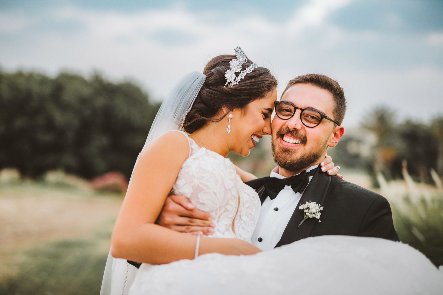 Joyful wedding couple sharing laughter during outdoor portrait session.