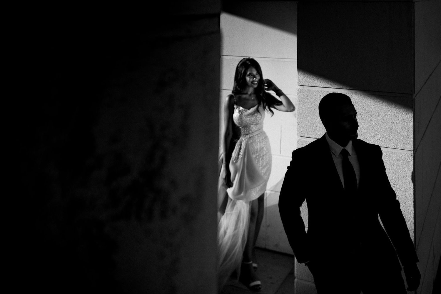 Black and white silhouette of wedding party walking in dramatic lighting.