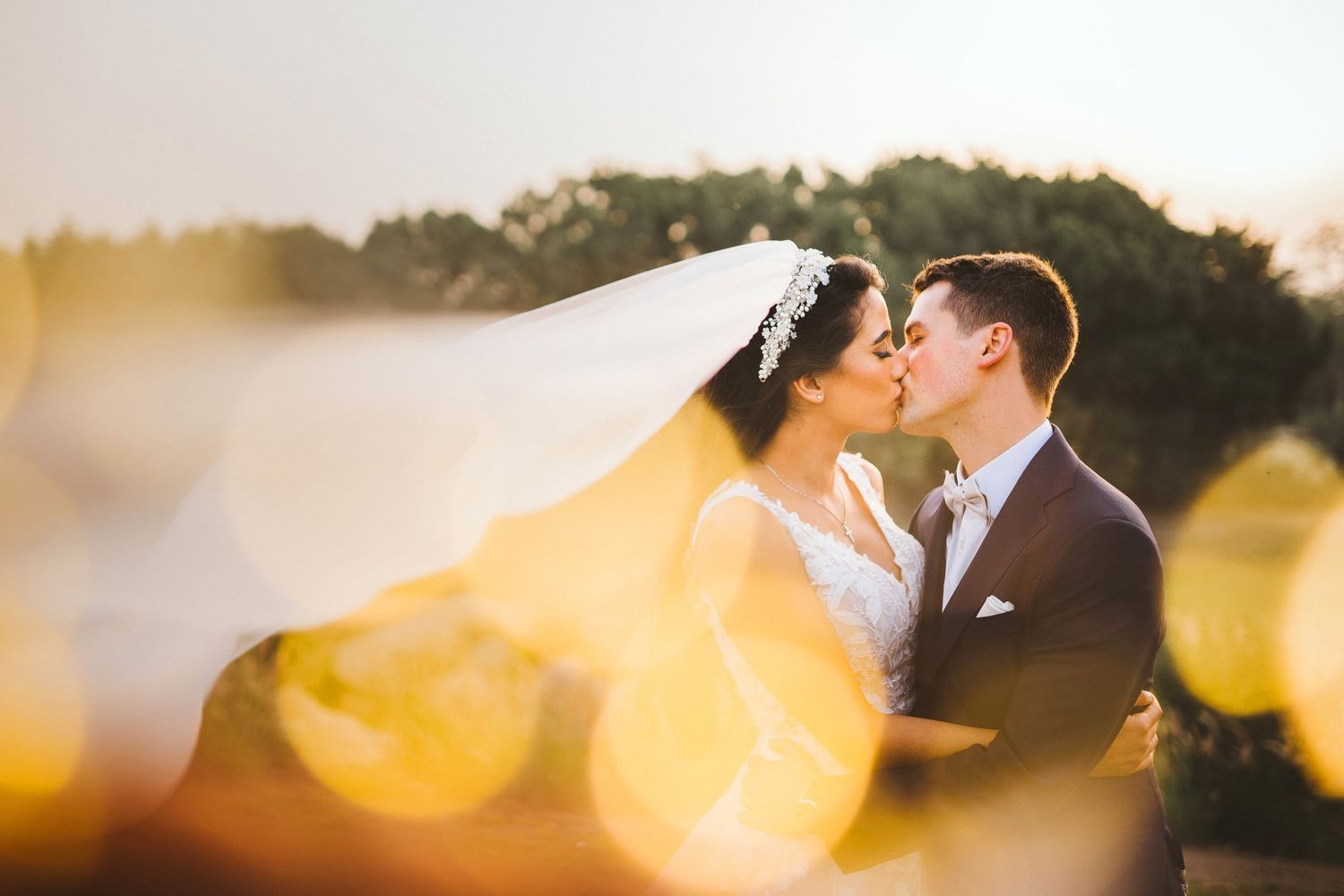 Golden hour wedding portrait with soft bokeh lights in the background.
