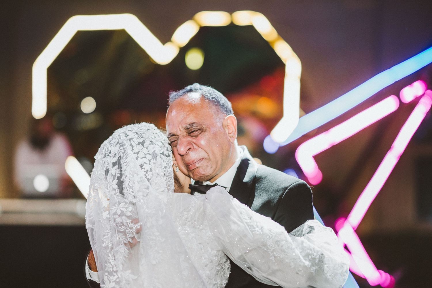 Wedding couple dancing under colorful neon lights at their reception celebration.