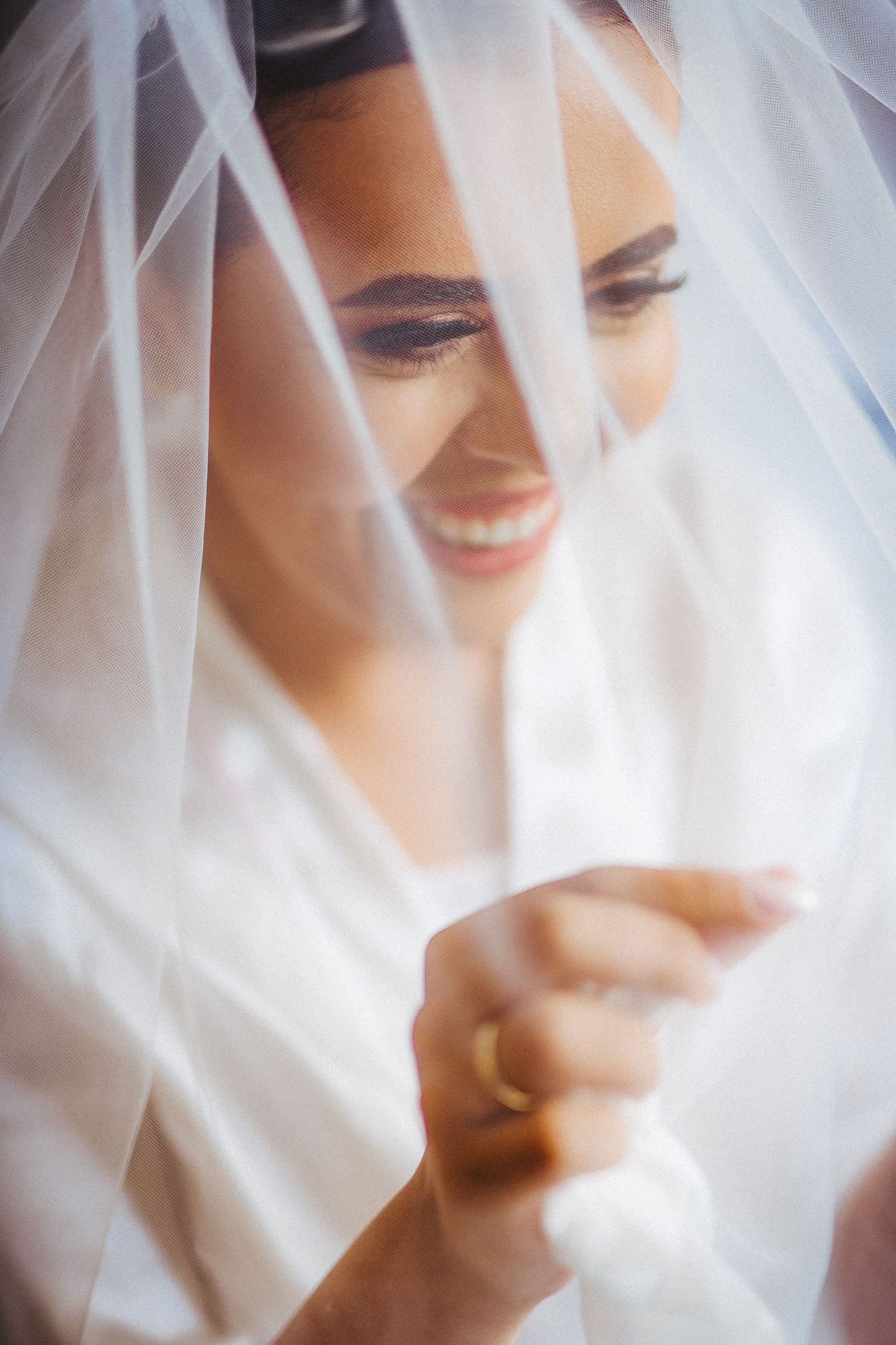 Close-up shots through delicate white wedding veil showing joyful expressions.