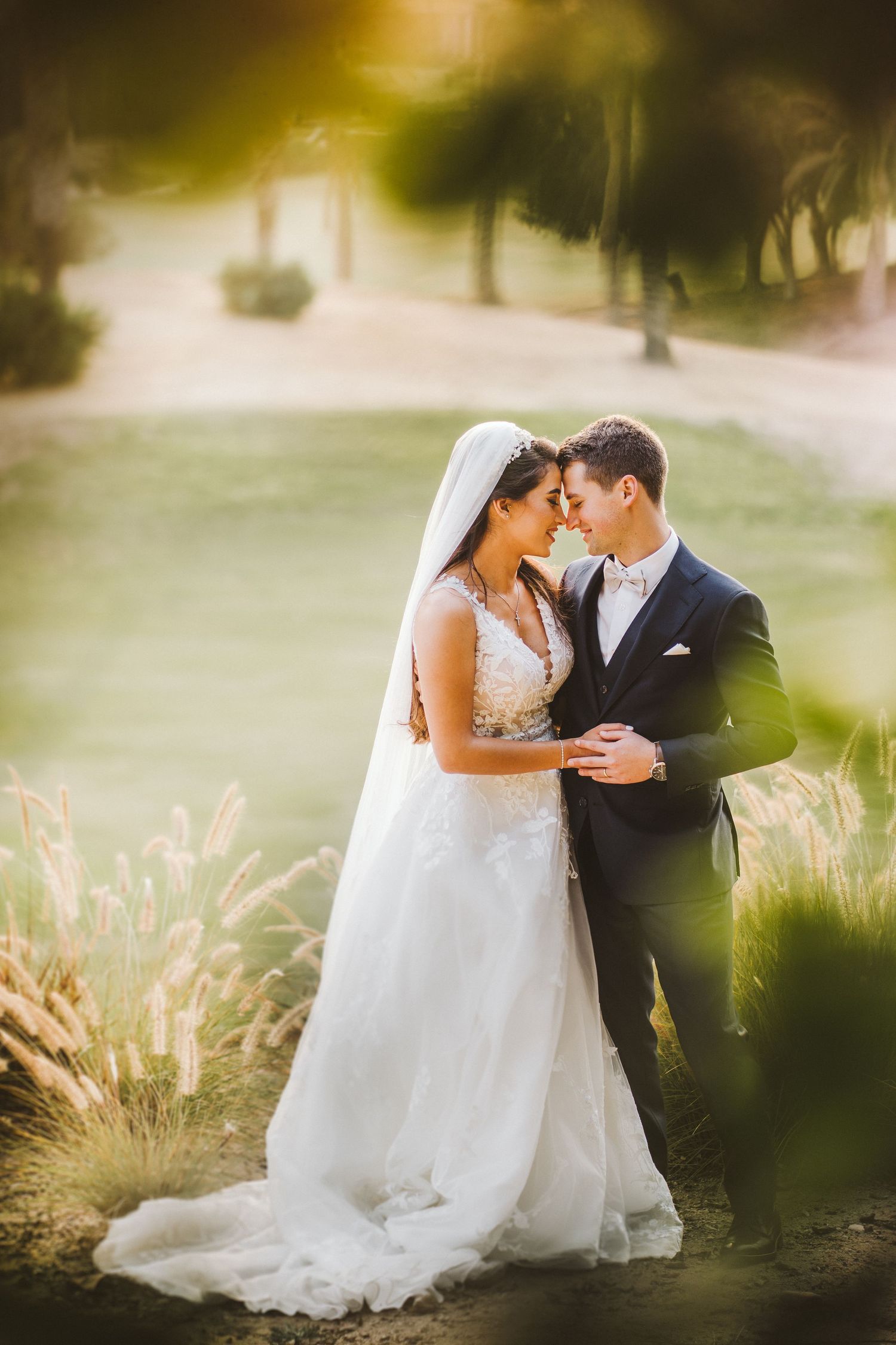 Romantic wedding portrait of couple embracing in garden with dreamy golden light.