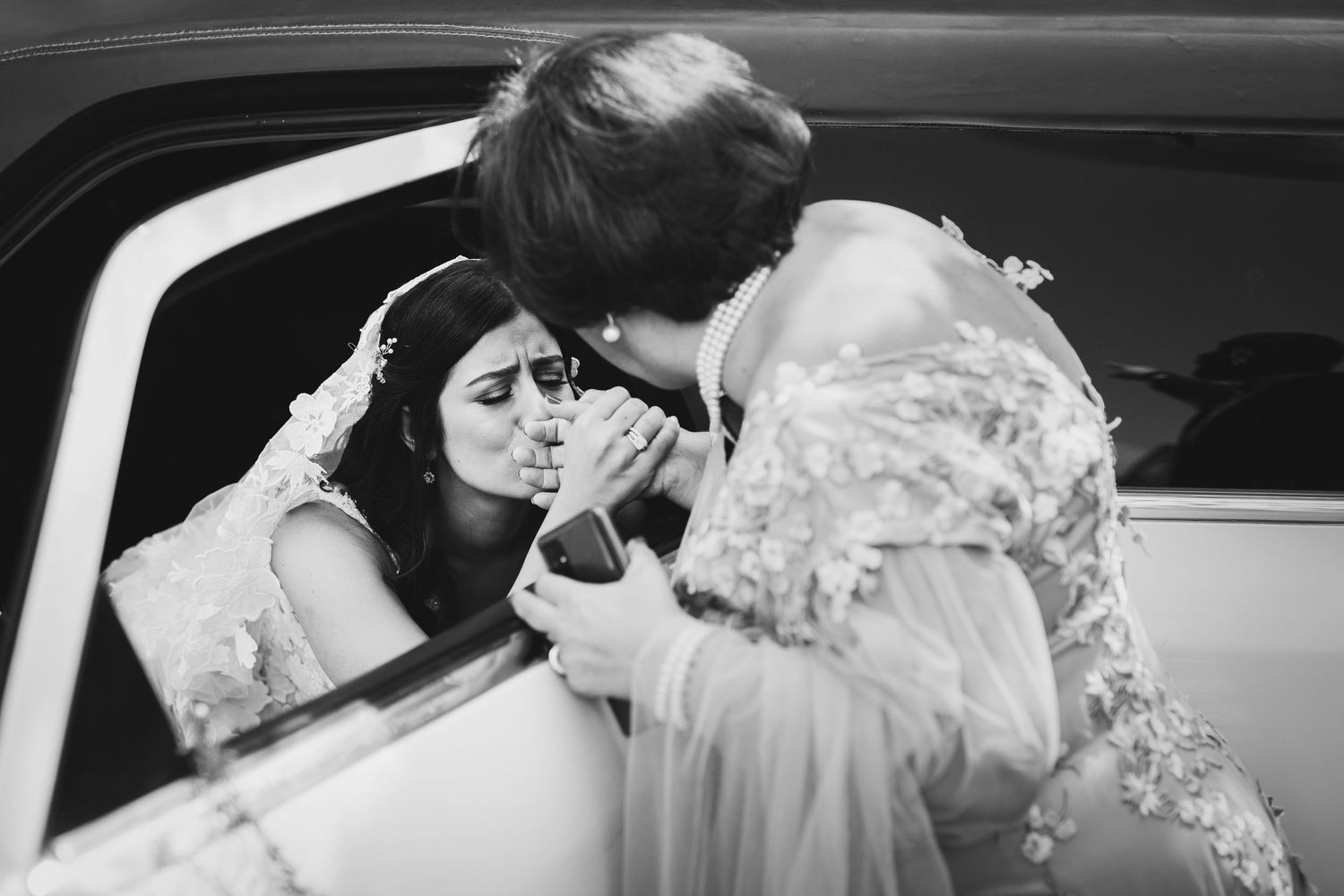 A vintage black and white photo showing a tender moment through a car window.