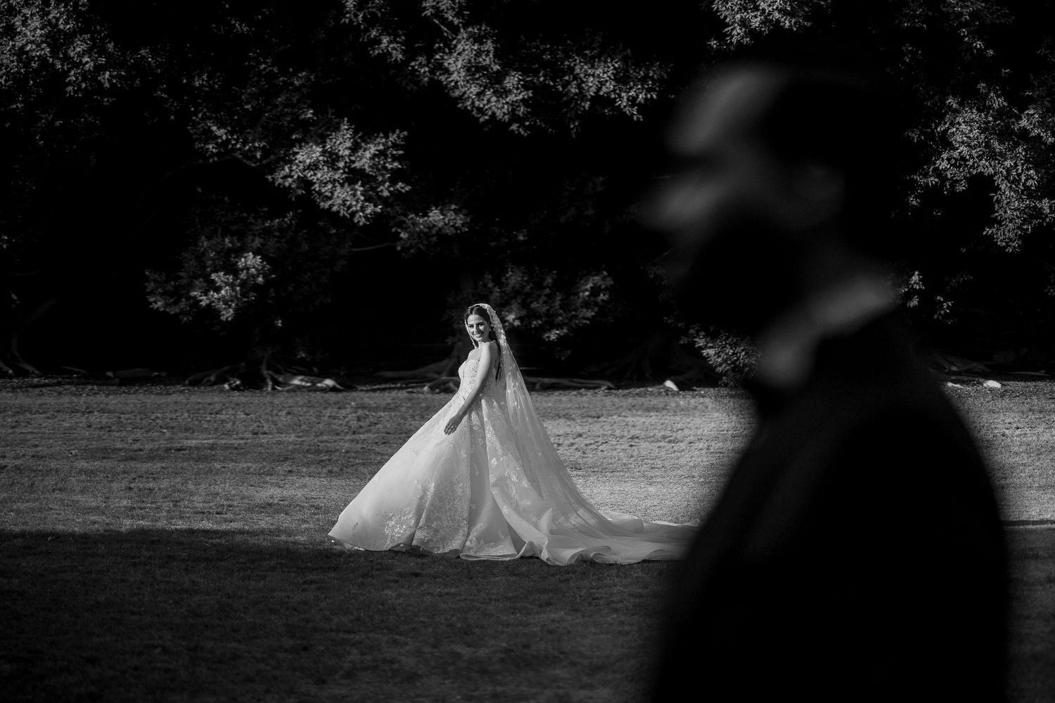 A dramatic black and white wedding photo with a bride in the distance.