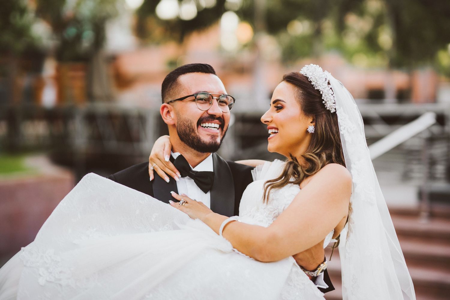 A joyful wedding moment captured on stairs with the groom carrying his bride.