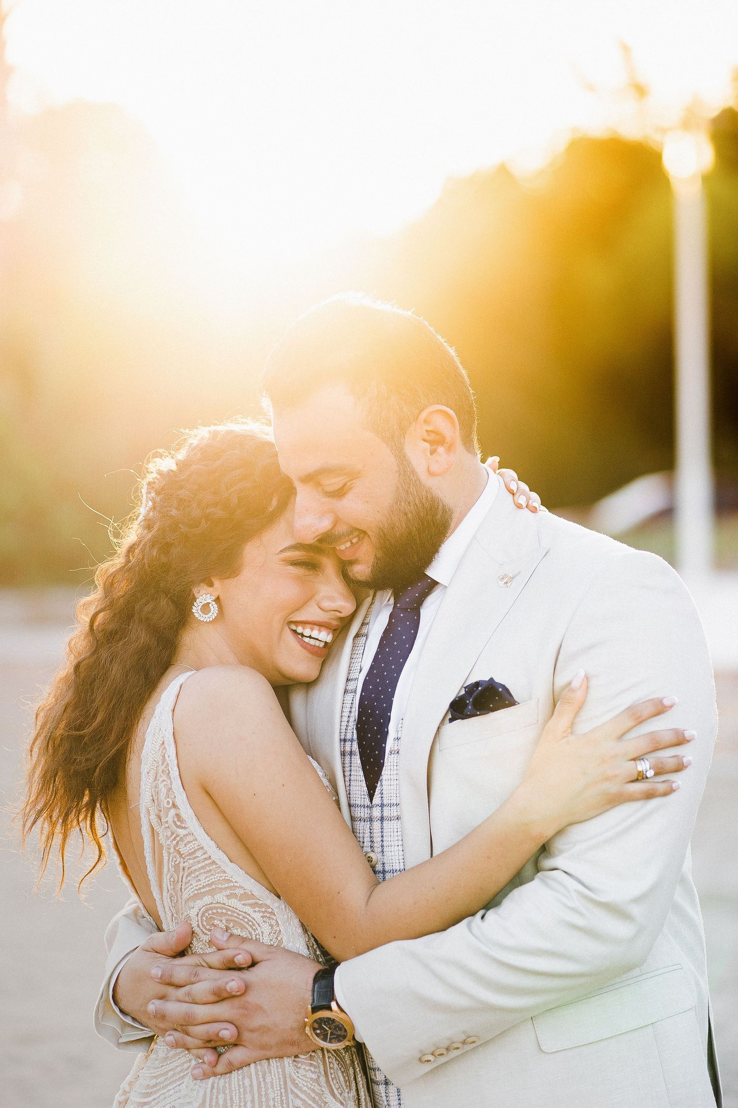 Romantic couple sharing intimate moment at sunset in formal wedding attire.