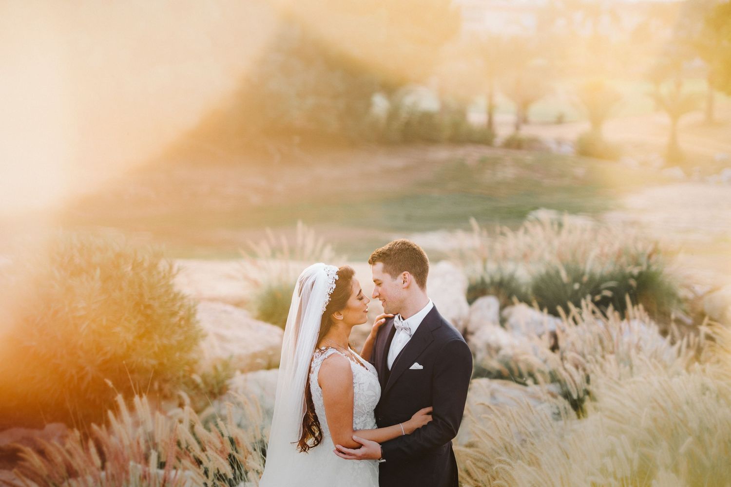 Romantic sunset portrait of newlyweds embracing in golden light.