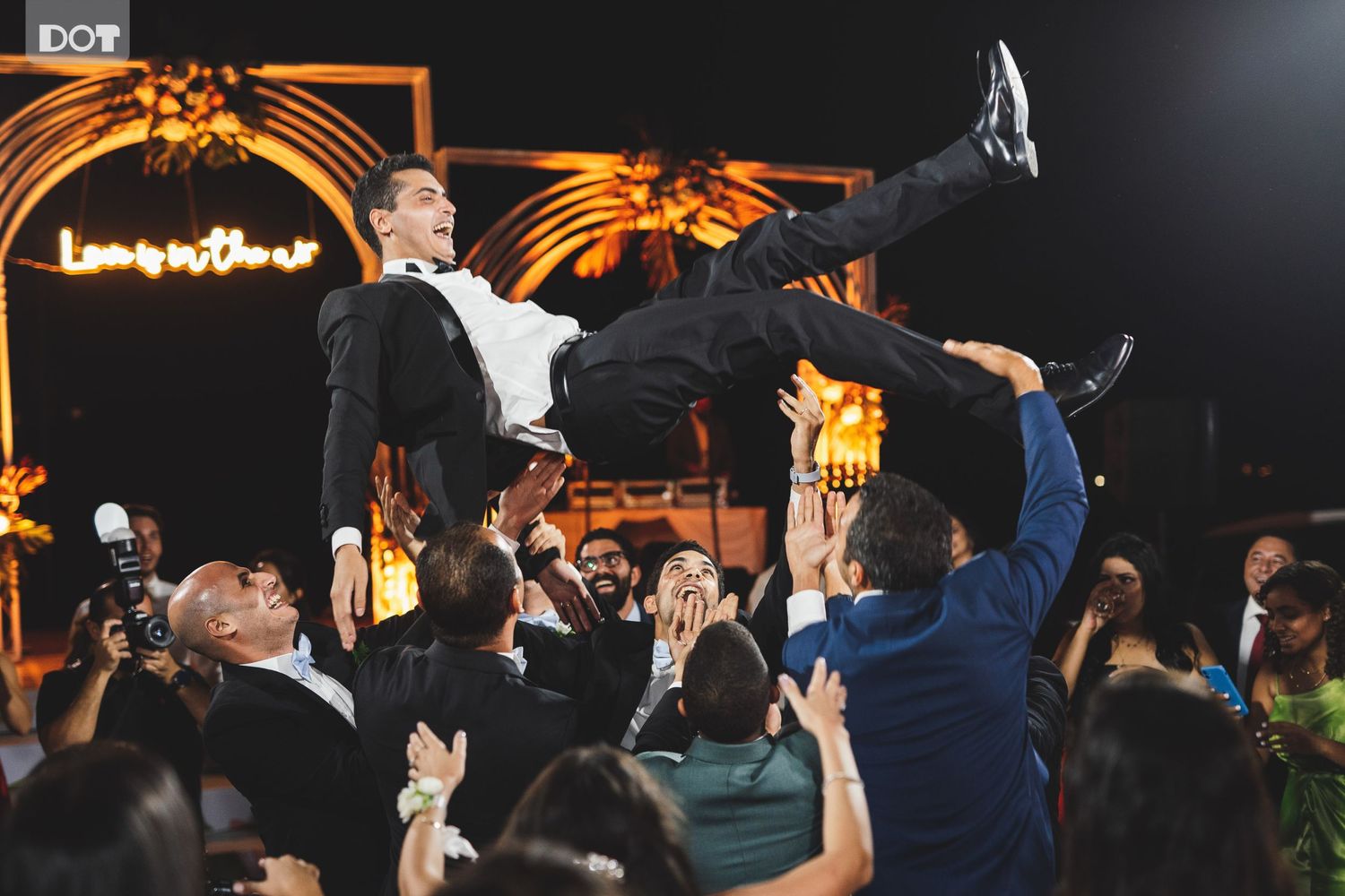 Wedding reception celebration with guest being lifted by crowd during party.
