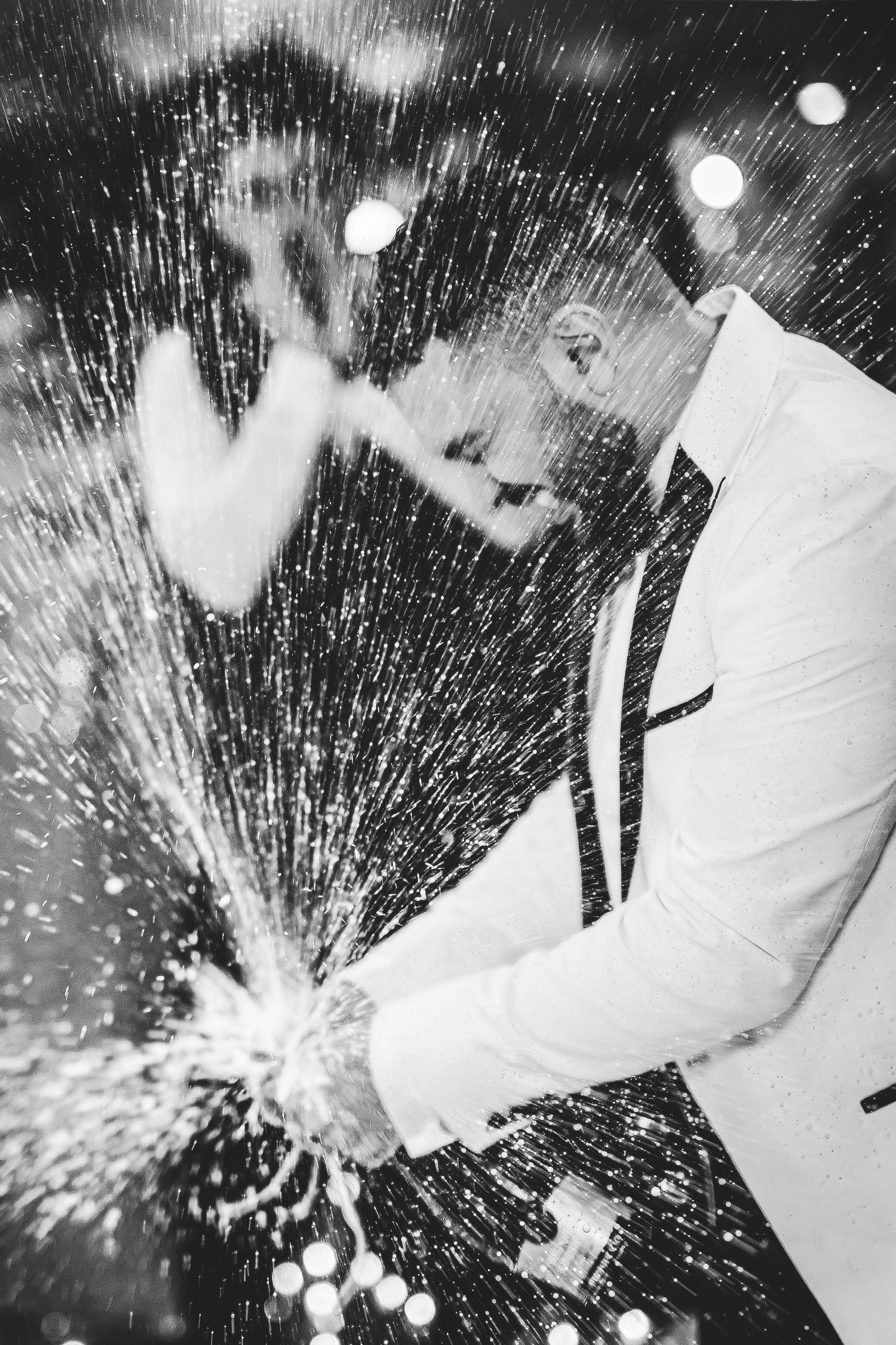 Black and white photo of water splashing dramatically around a wedding dress.
