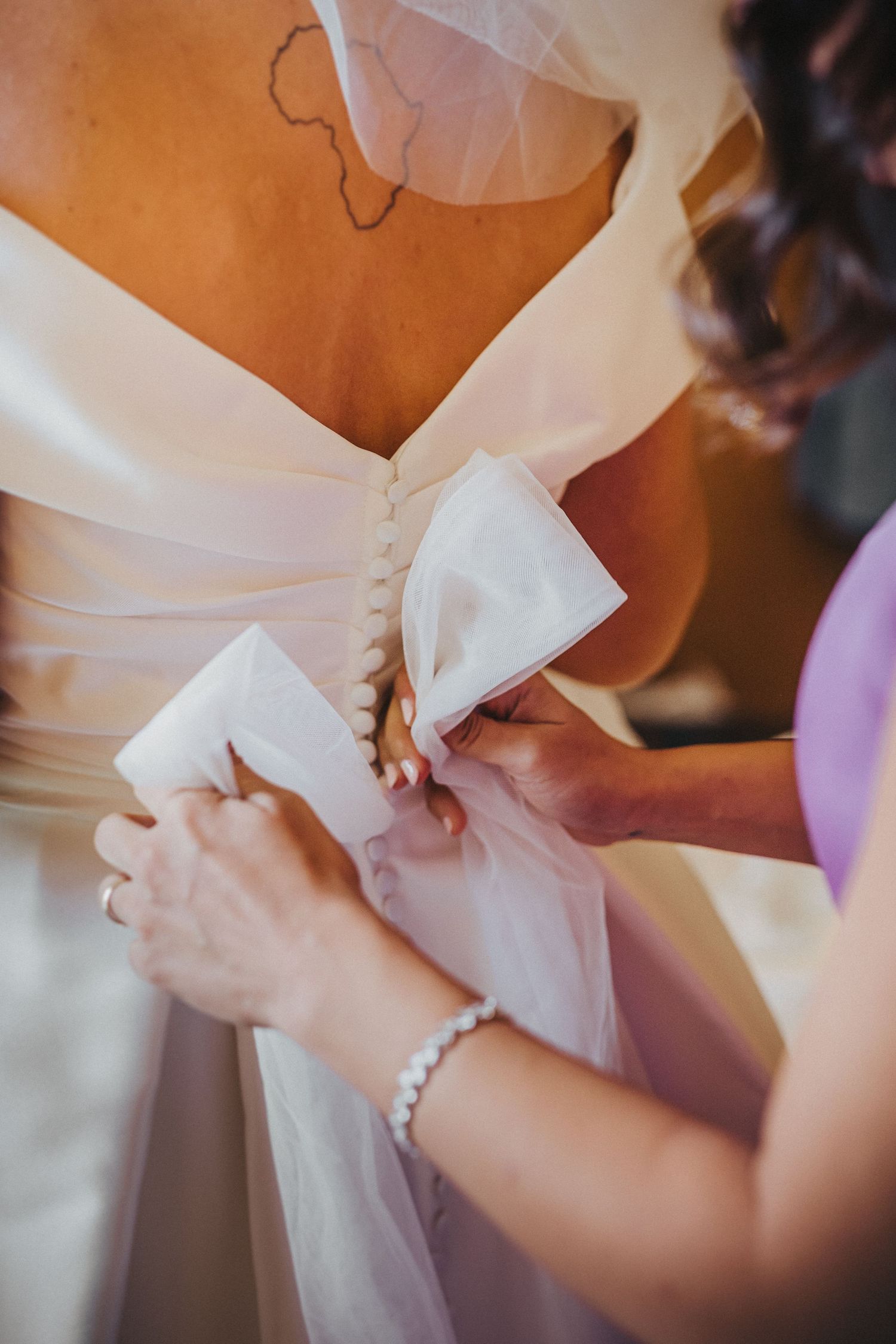 Close-up detail shot of hands adjusting a white dress bow.