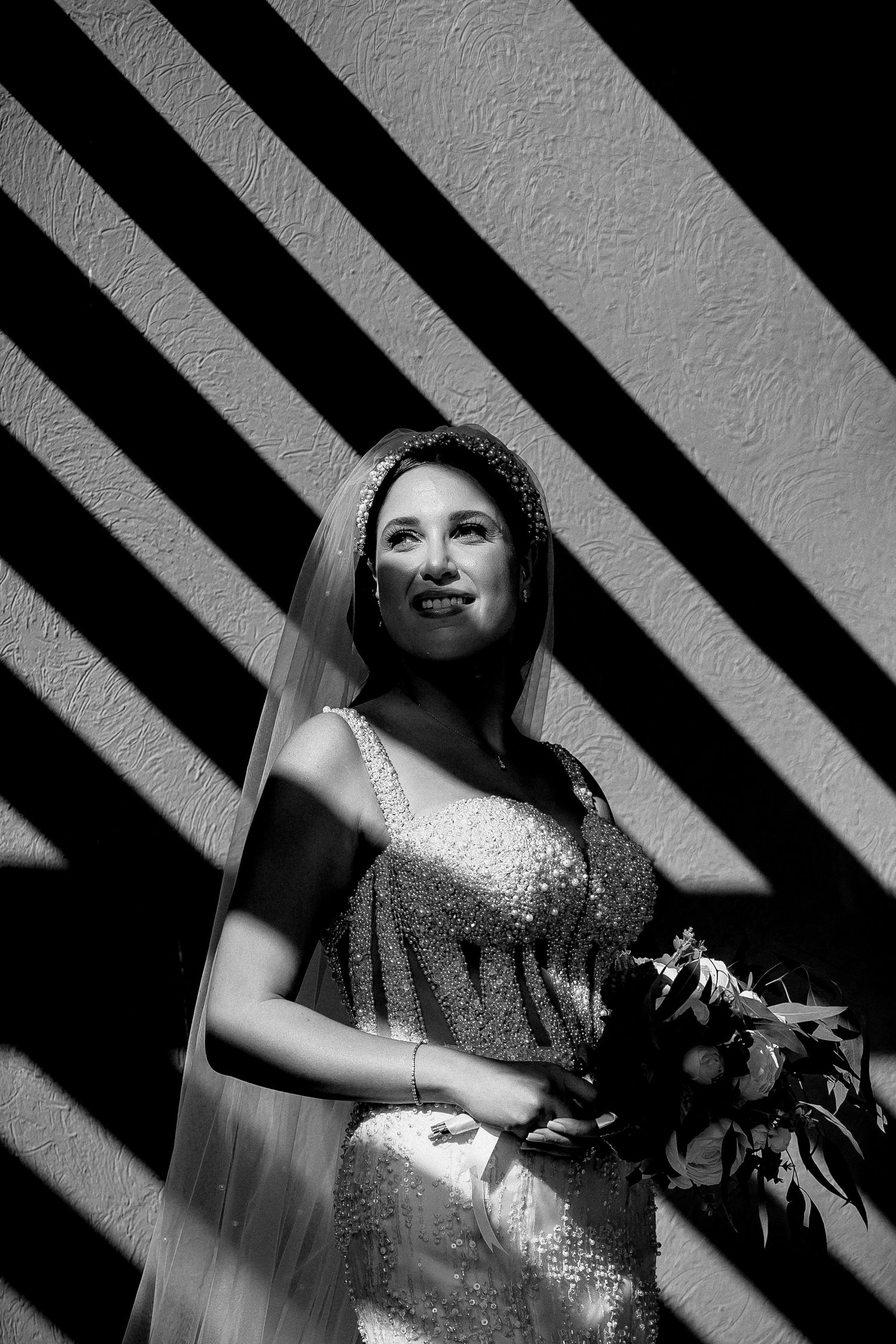 Dramatic black and white portrait with striking diagonal shadow patterns.