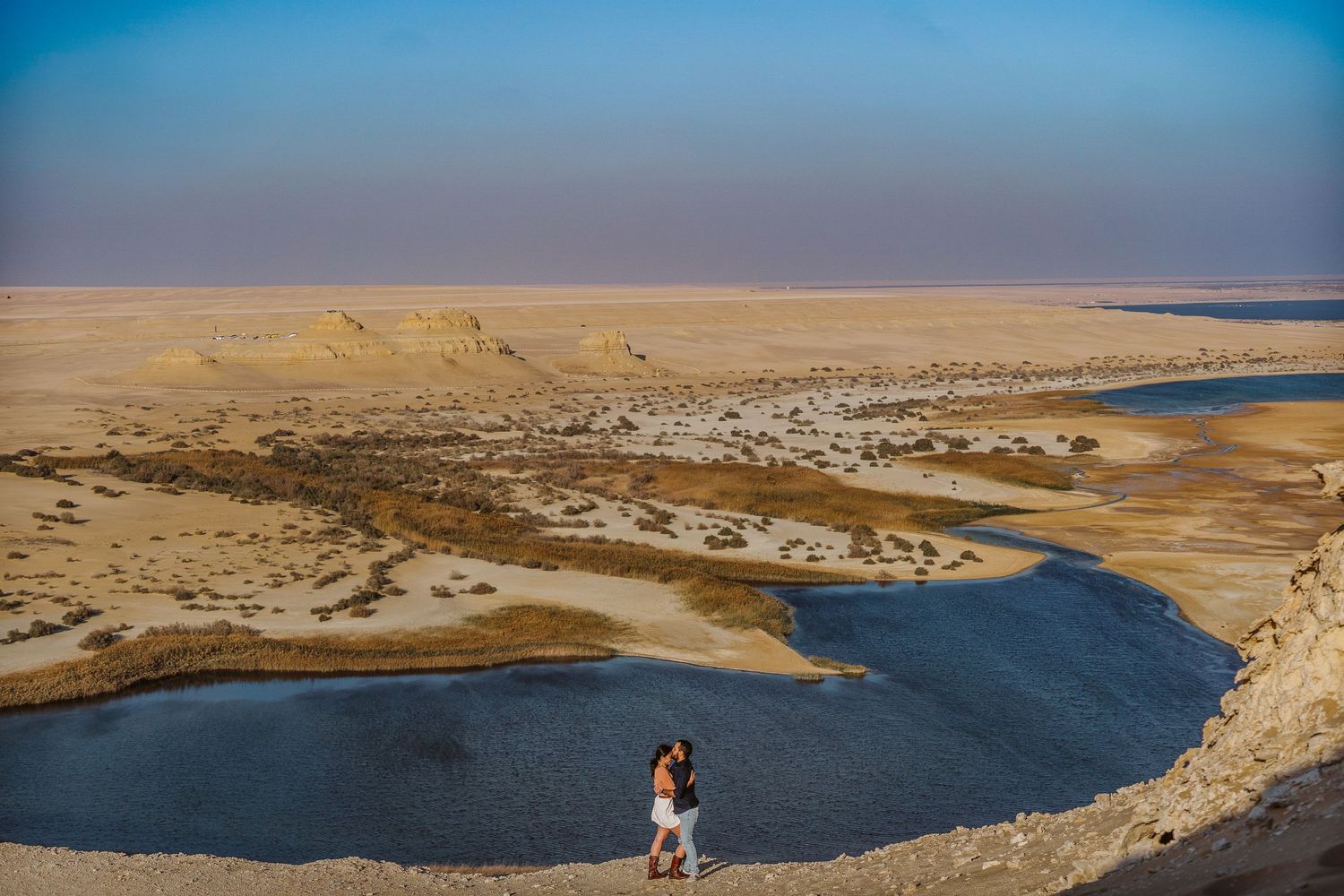 Panoramic view of a desert coastline with blue water and sandy shores.