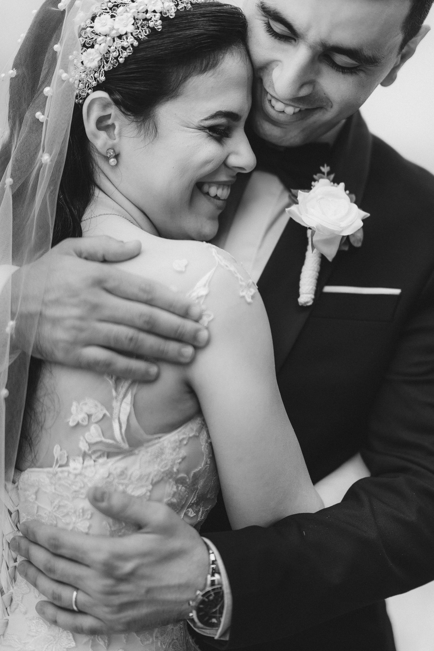 Black and white intimate wedding portrait showing genuine laughter and embrace.