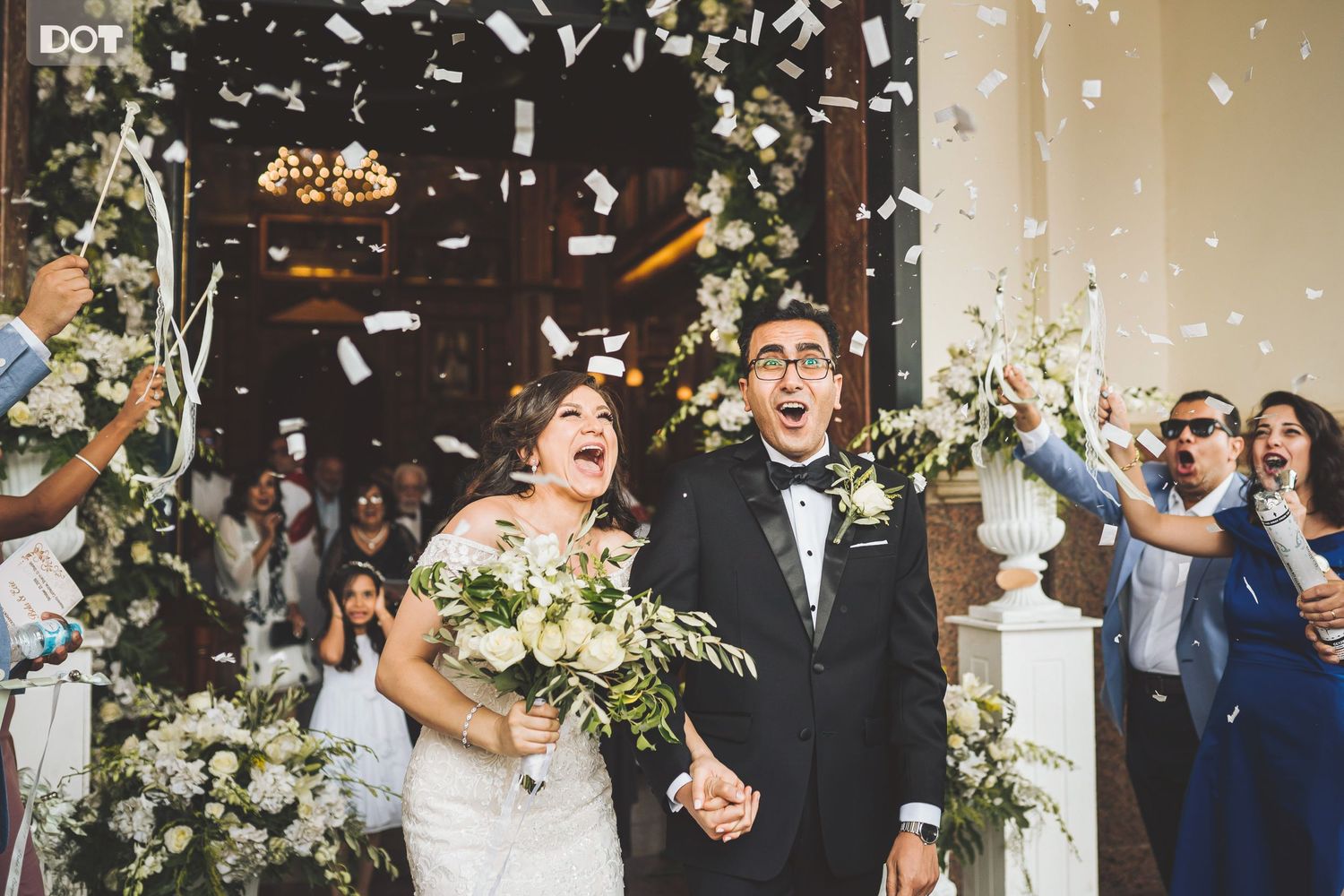 Wedding guests celebrate by throwing confetti and flower petals during a joyous outdoor ceremony.