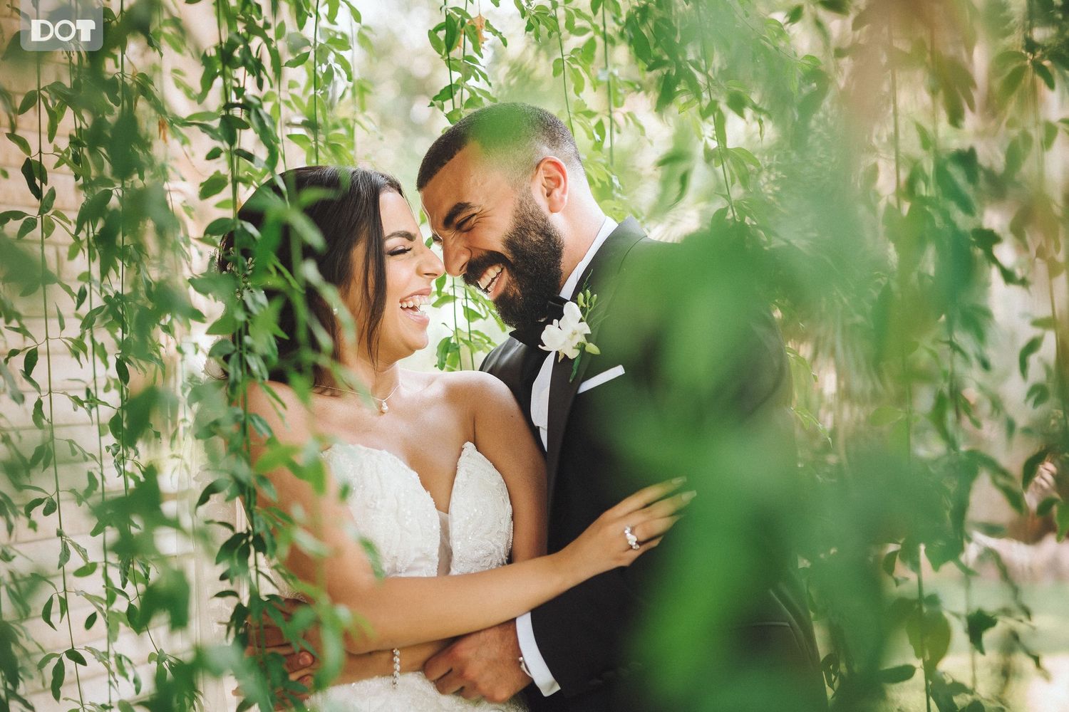 Intimate wedding moment captured through hanging greenery and natural foliage.