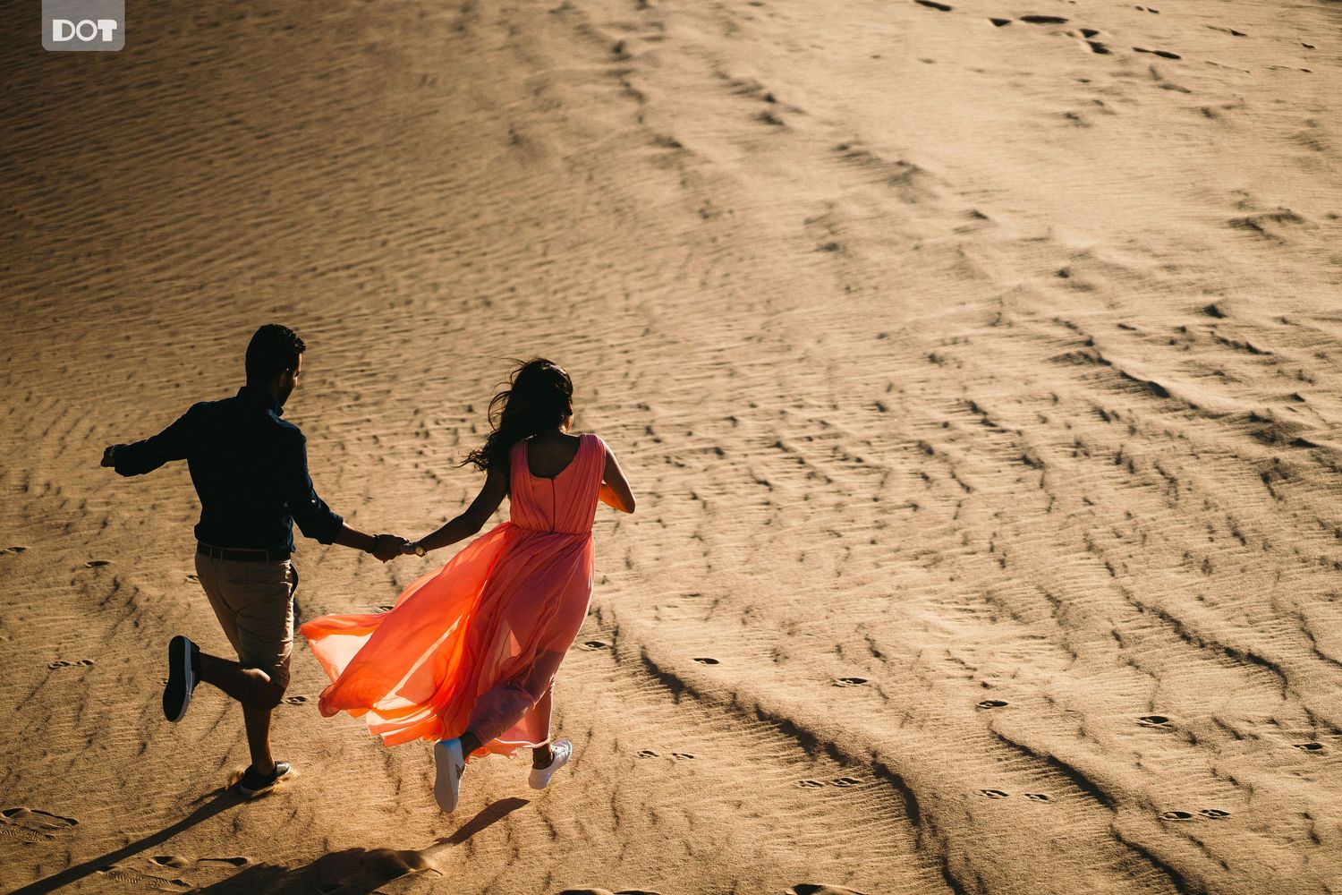 Silhouettes play and run across sandy dunes during golden sunset.