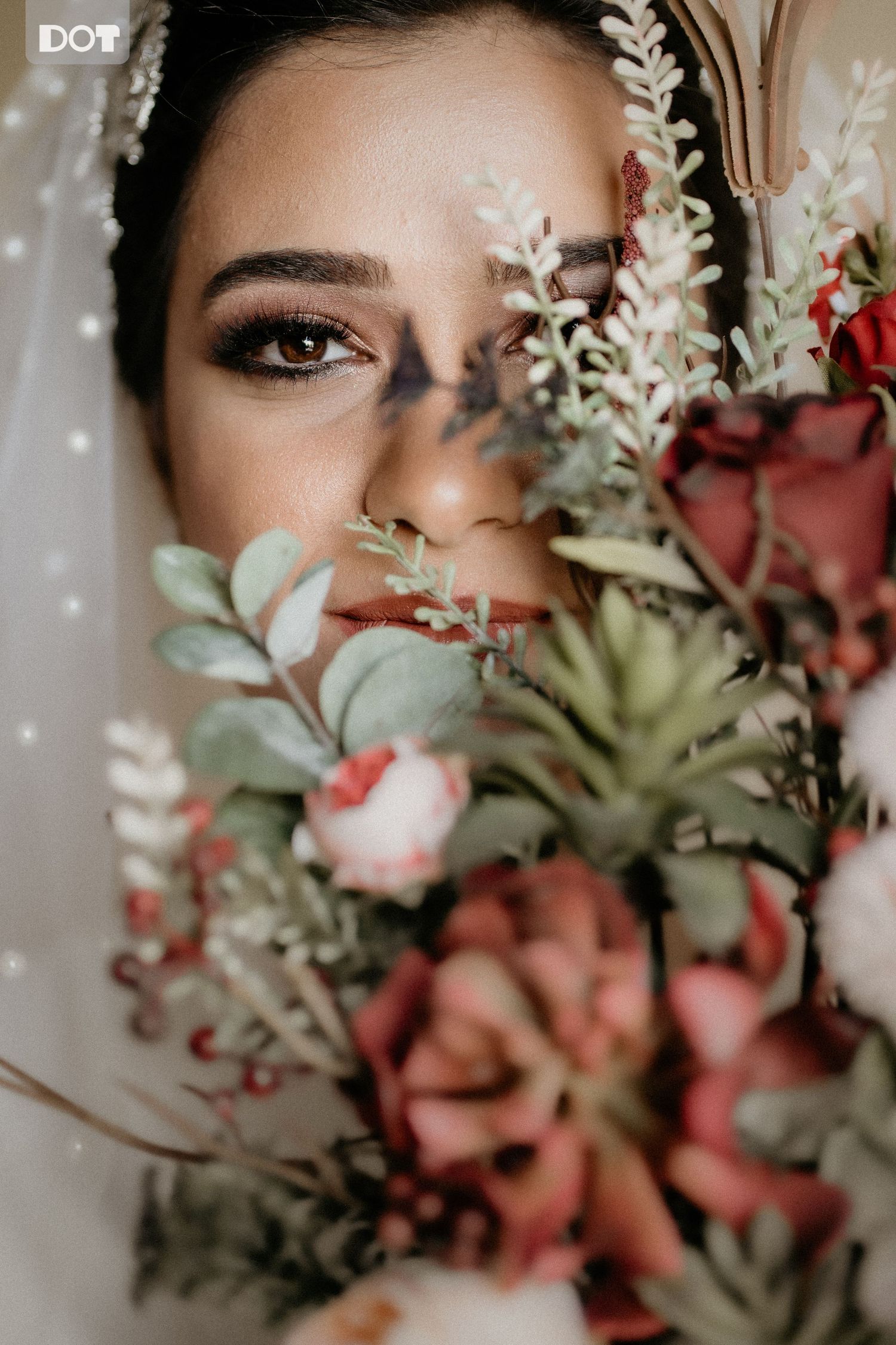 Artistic portrait through flowers and foliage creating a dreamy, romantic effect.
