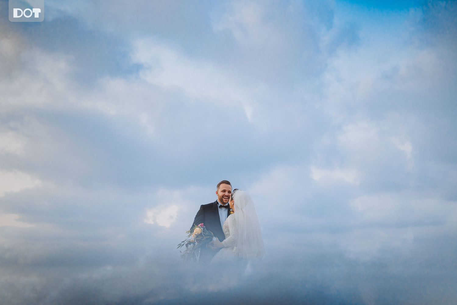 Dramatic cloudy sky creates moody atmosphere for outdoor wedding photography.