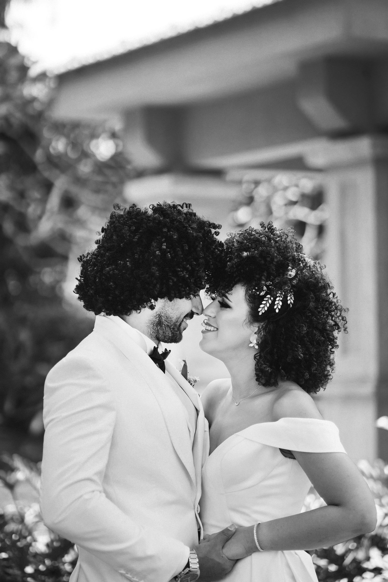 Black and white portrait of couple sharing intimate moment in garden setting.