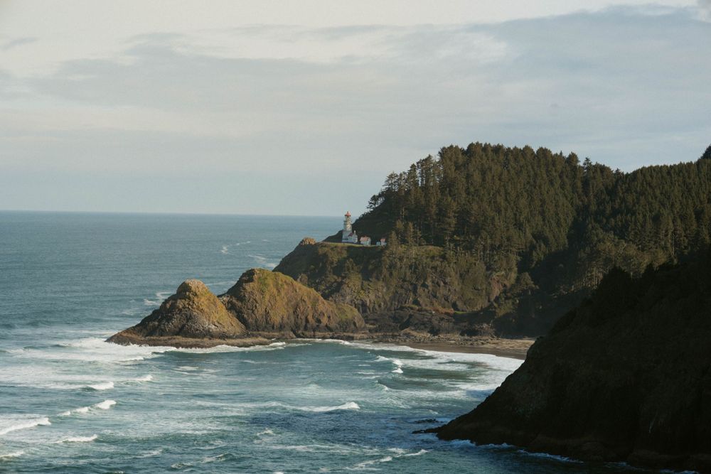 Dramatic panorama of rugged Oregon coastline with crashing waves and rocky headlands.