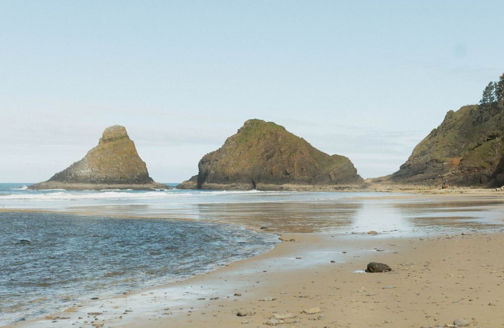 Panoramic view of a rocky coastline with sea stacks and sandy beach at low tide.